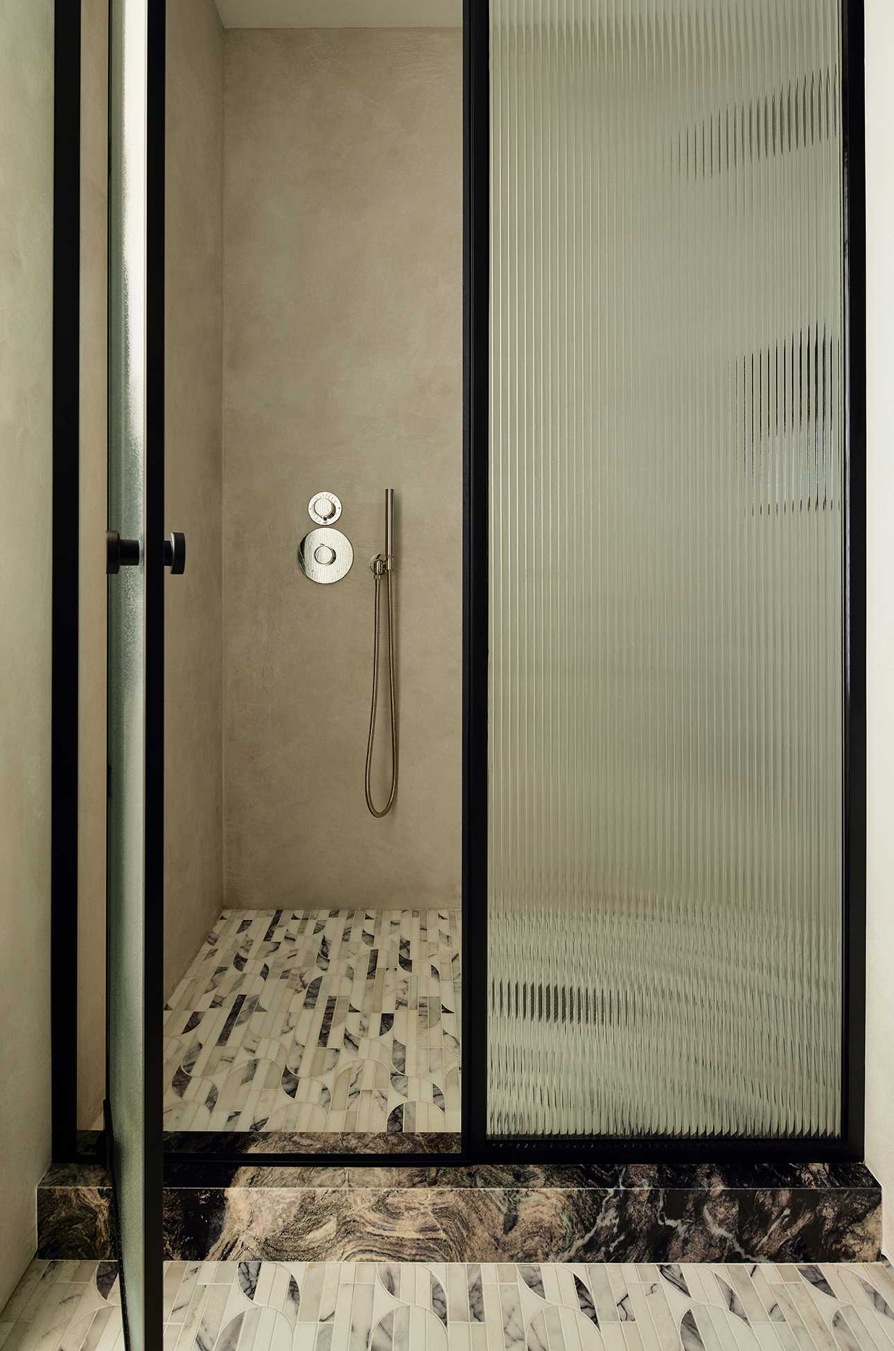 In this bathroom, an arched mirror follows the curve of the wall, while the floor tiles add a subtle pattern, which flows through to the shower.