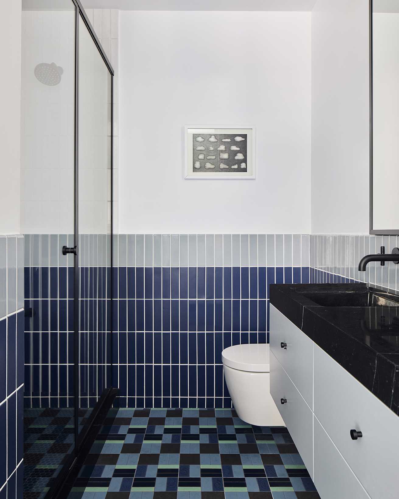 In this bathroom, tiles in various shades of blue have been paired with grey and green for a contemporary look.