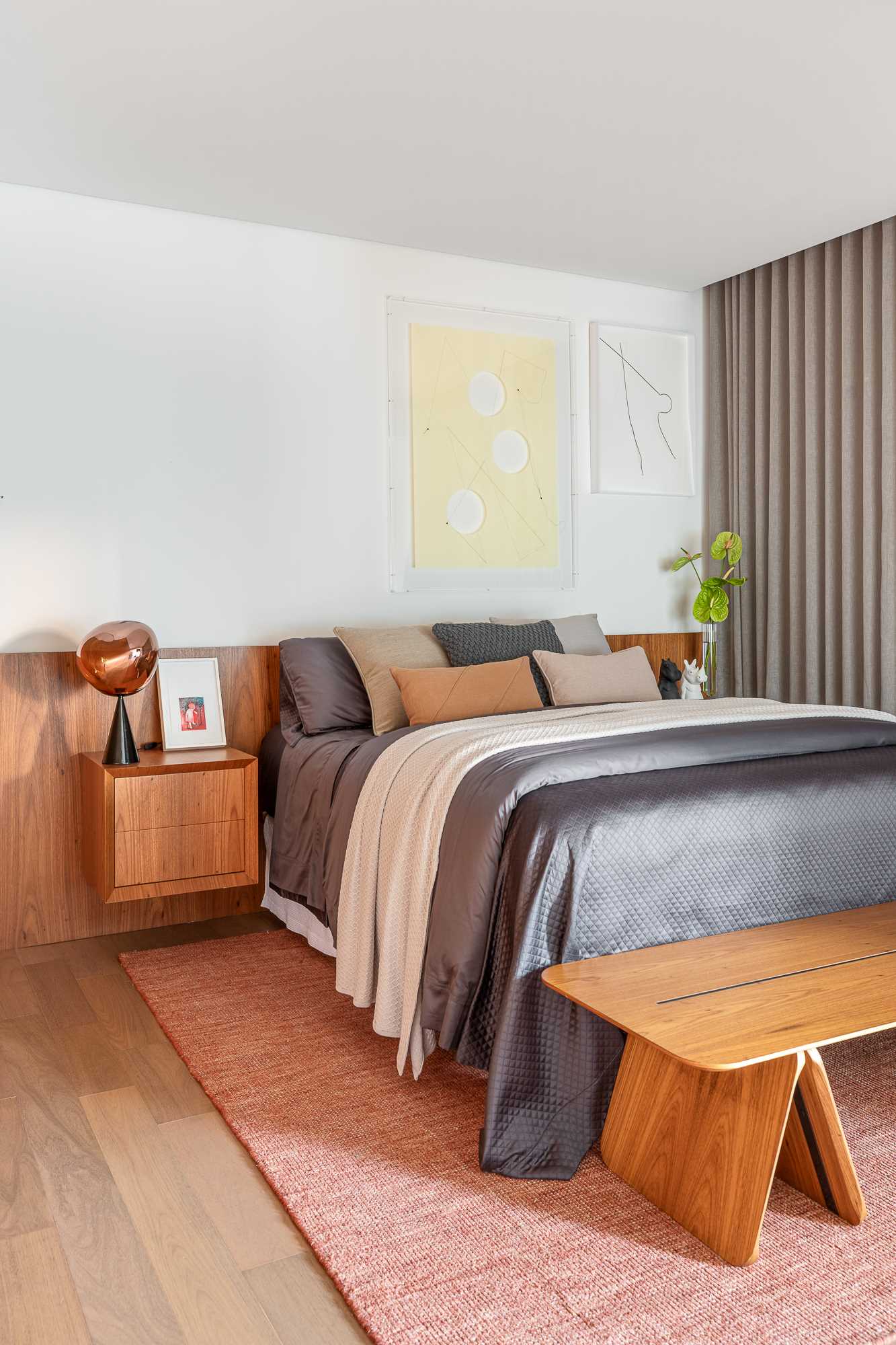 A modern bedroom with hidden lighting, a wood headboard, and wall of cabinets.