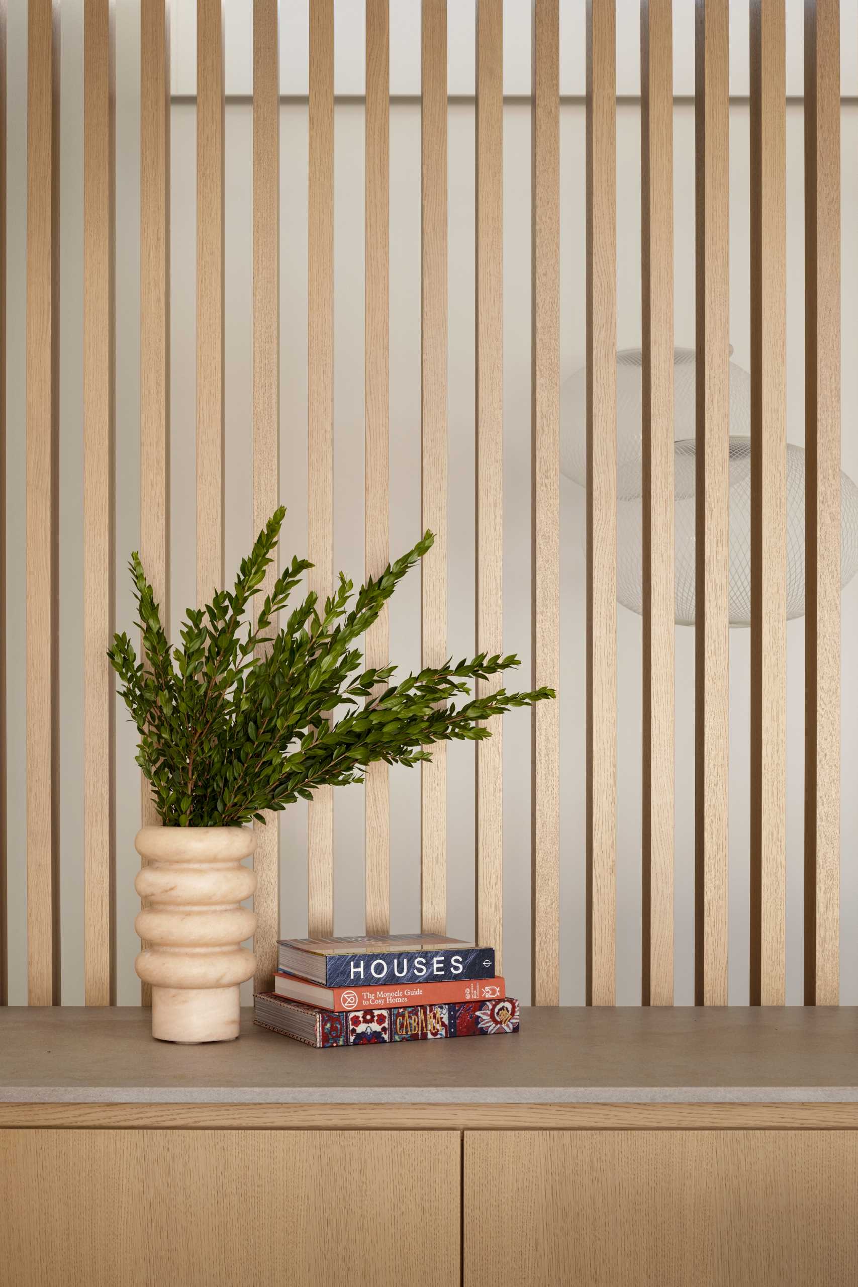 Oak slat partitions, like this one behind the credenza, carry the mid-century aesthetic throughout the home, dividing spaces while allowing light to flow between.