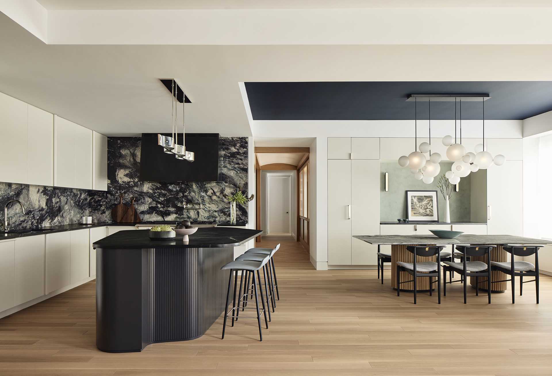 This modern kitchen is defined on one side by a stormy blue marble backsplash (Phoenix marble from ABC Stone), it is anchored by a black soapstone island in the shape of a rounded, asymmetrical pentagon, surrounded by seating for casual family dining.