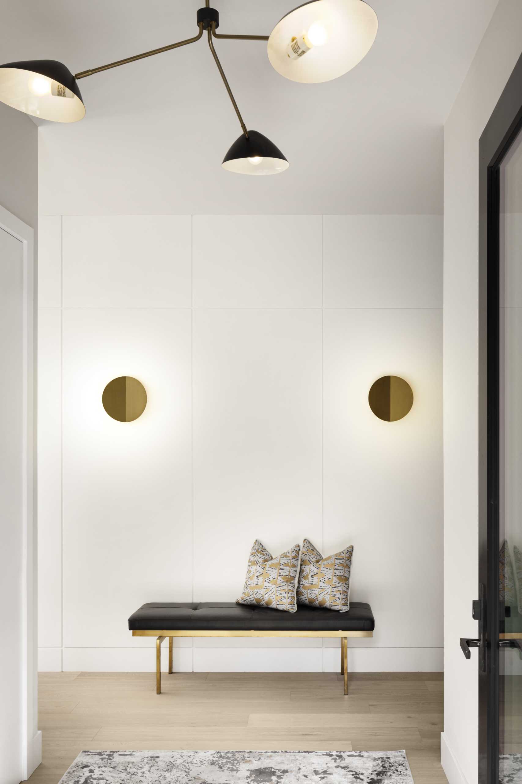 A minimalist foyer with a bench and metallic accents.