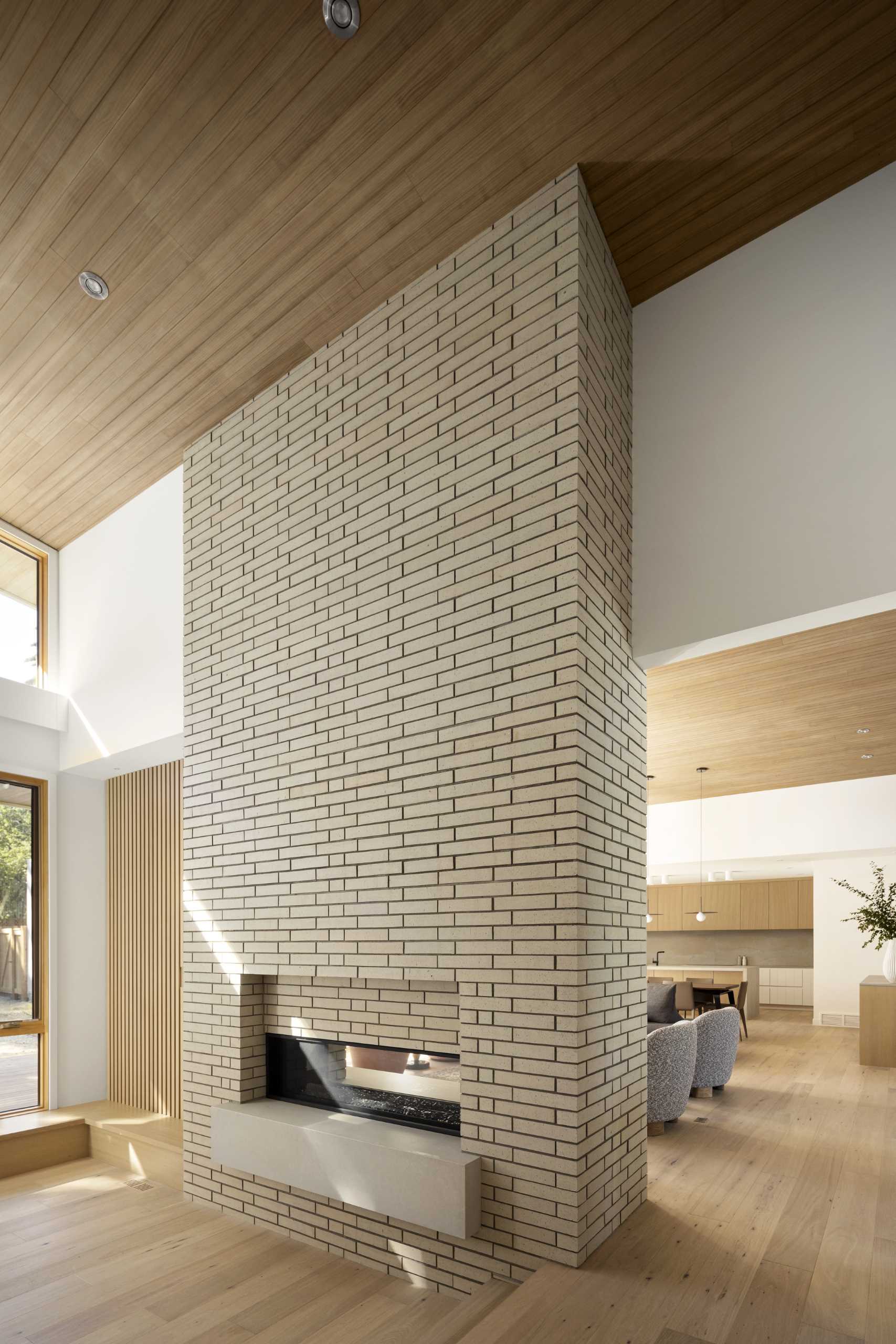 In the living room, there's a double-sided fireplace surrounded by brick.