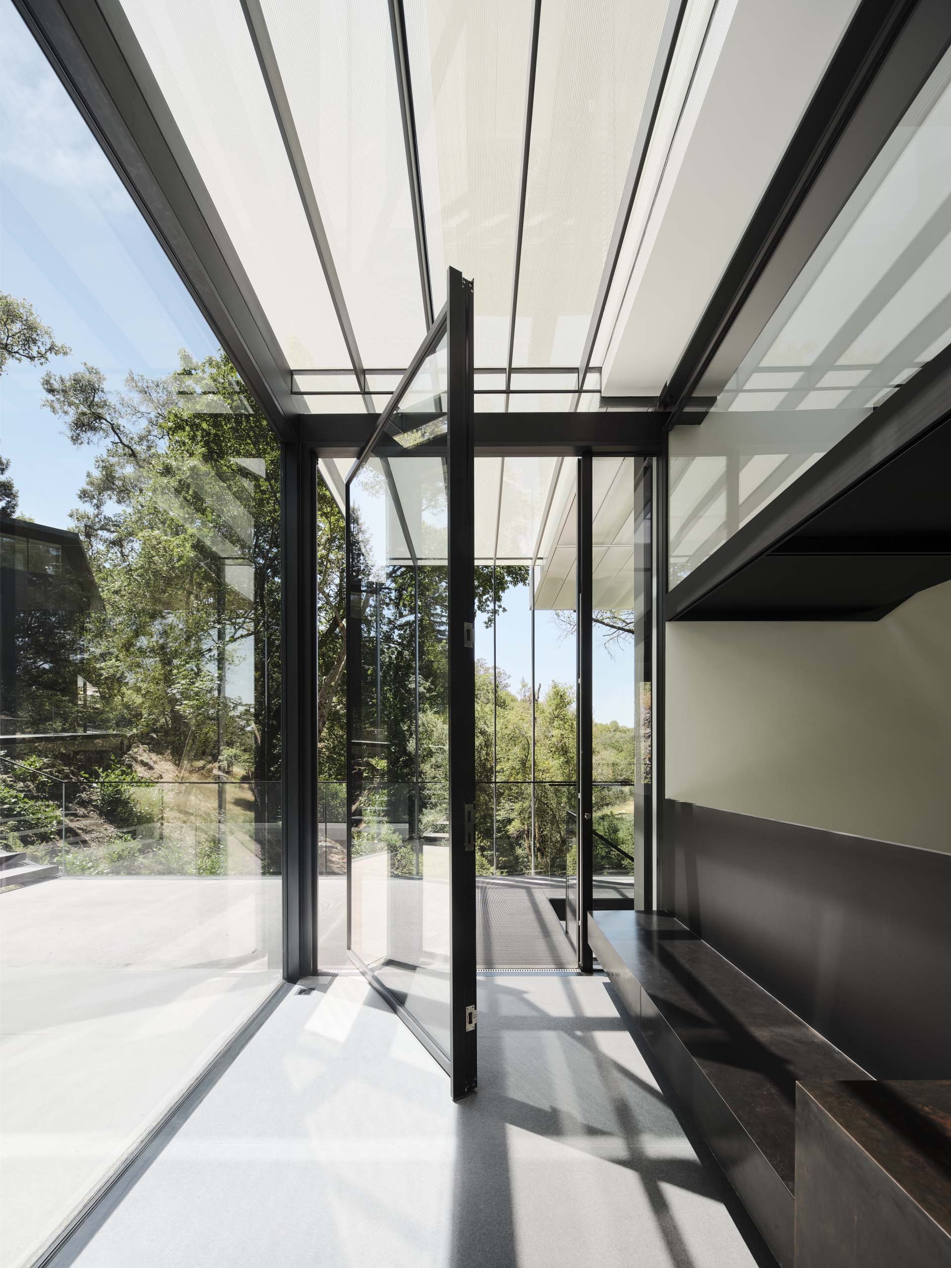 A pivoting glass front door welcomes visitors to this modern home.