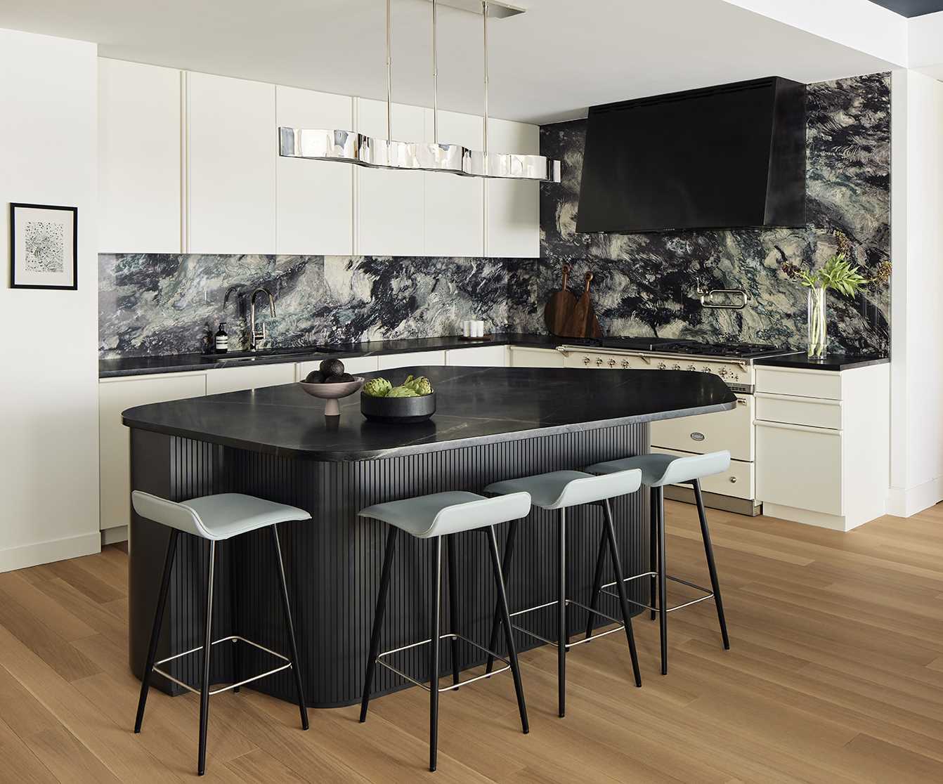 This modern kitchen is defined on one side by a stormy blue marble backsplash (Phoenix marble from ABC Stone), it is anchored by a black soapstone island in the shape of a rounded, asymmetrical pentagon, surrounded by seating for casual family dining.