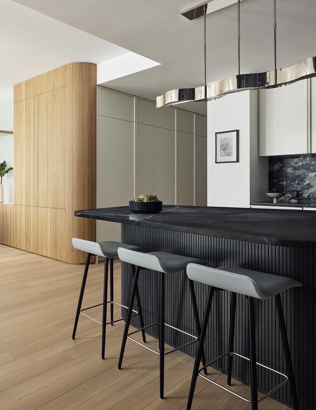 This modern kitchen is defined on one side by a stormy blue marble backsplash (Phoenix marble from ABC Stone), it is anchored by a black soapstone island in the shape of a rounded, asymmetrical pentagon, surrounded by seating for casual family dining.