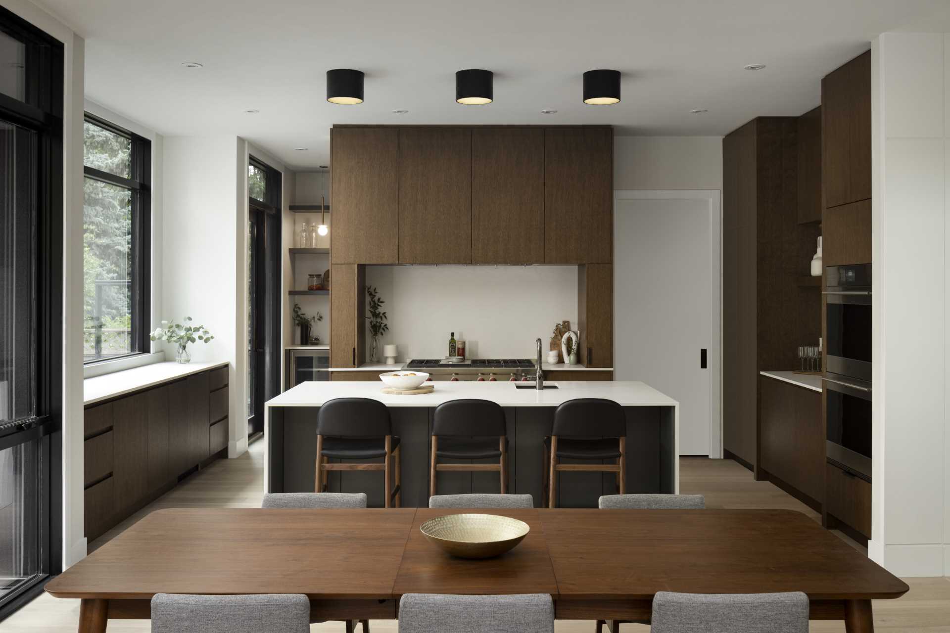 The kitchen is located behind the dining area and has dark wood cabinets that match the dining table. A central island adds countertop space, while cabinets on the walls on either side add storage. 