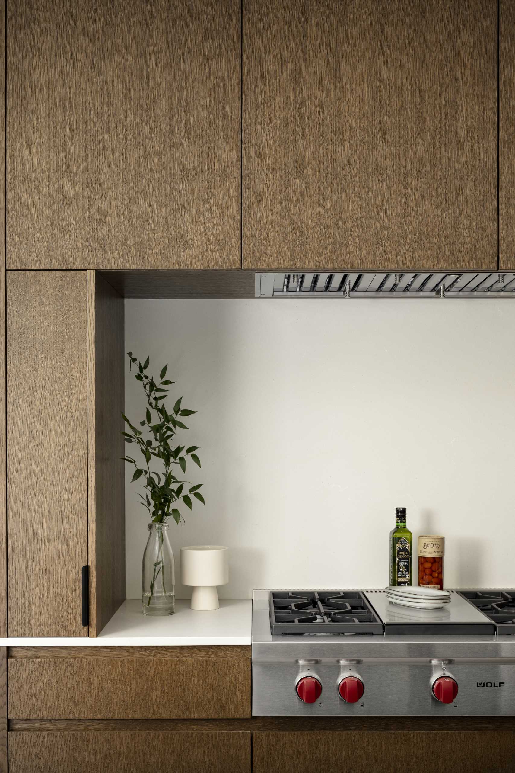 The kitchen is located behind the dining area and has dark wood cabinets that match the dining table. A central island adds countertop space, while cabinets on the walls on either side add storage. 