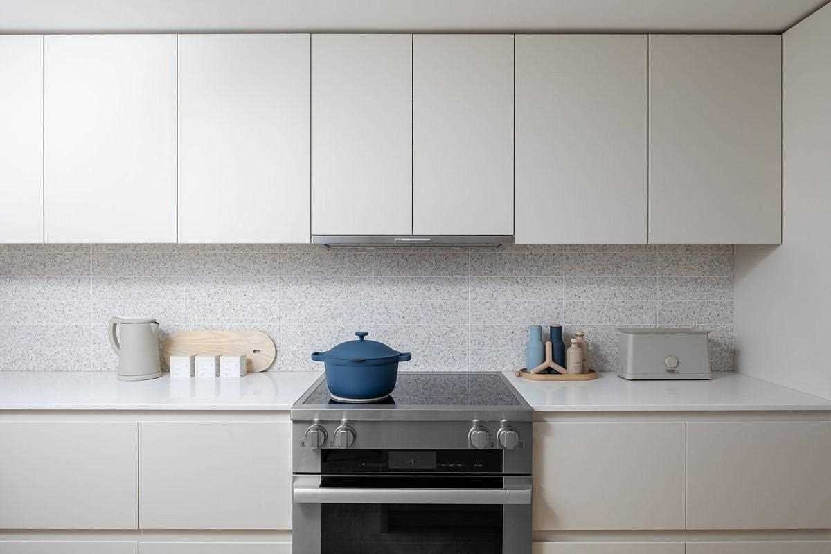 In this modern kitchen, terrazzo tiles add a unique and artistic touch, while hardware-free cabinets and integrated appliances give the space a minimalist appearance.