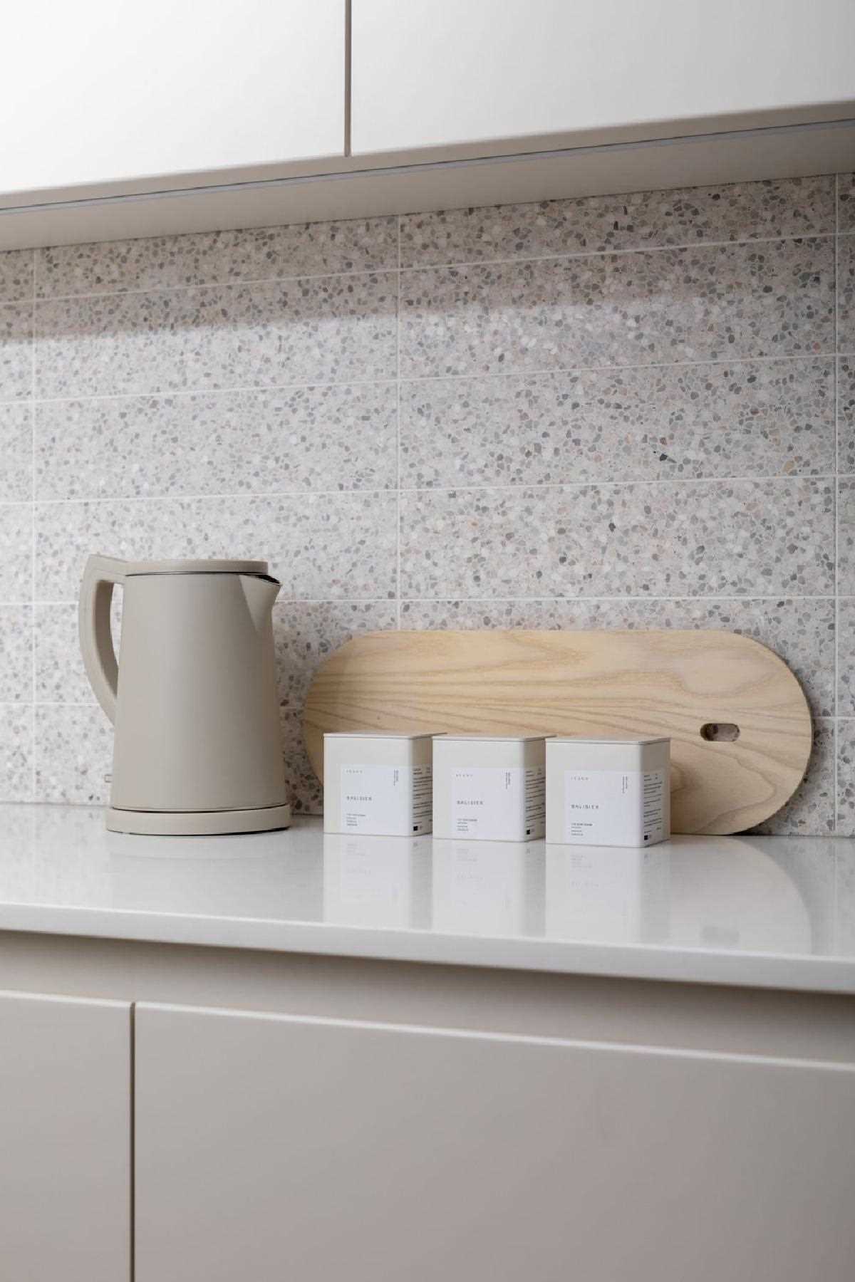 In this modern kitchen, terrazzo tiles add a unique and artistic touch, while hardware-free cabinets and integrated appliances give the space a minimalist appearance.