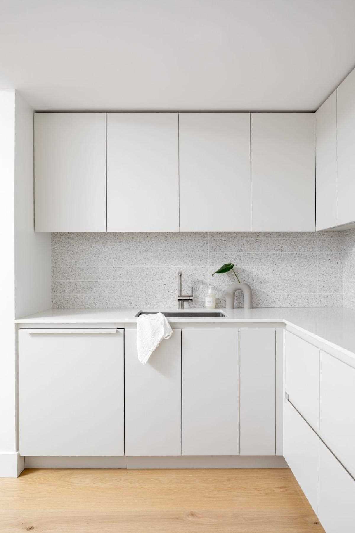 In this modern kitchen, terrazzo tiles add a unique and artistic touch, while hardware-free cabinets and integrated appliances give the space a minimalist appearance.