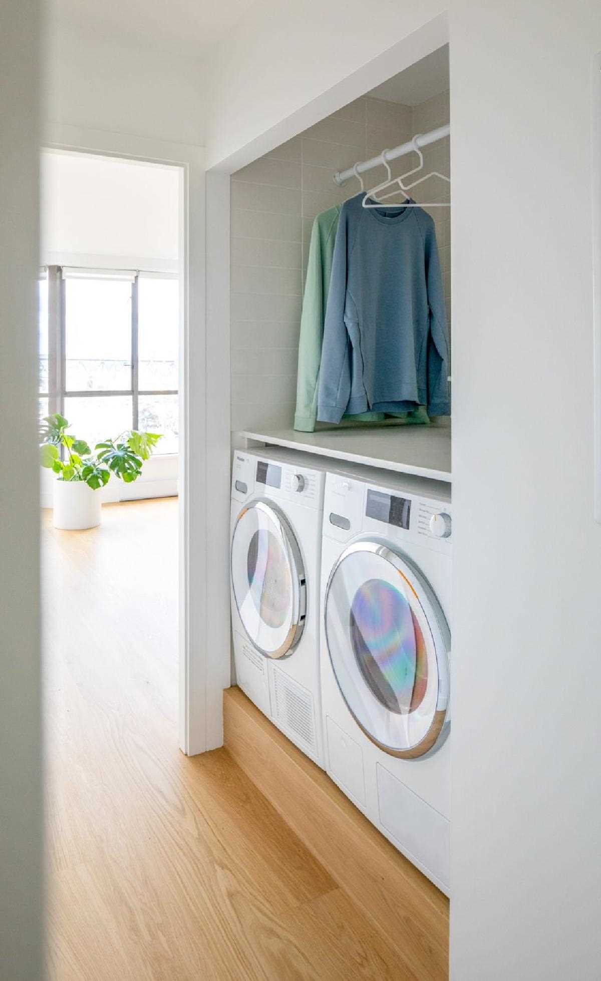 A laundry space is tucked away, with the washer and dryer raised, and a tiled area becomes the backdrop for drying clothes.