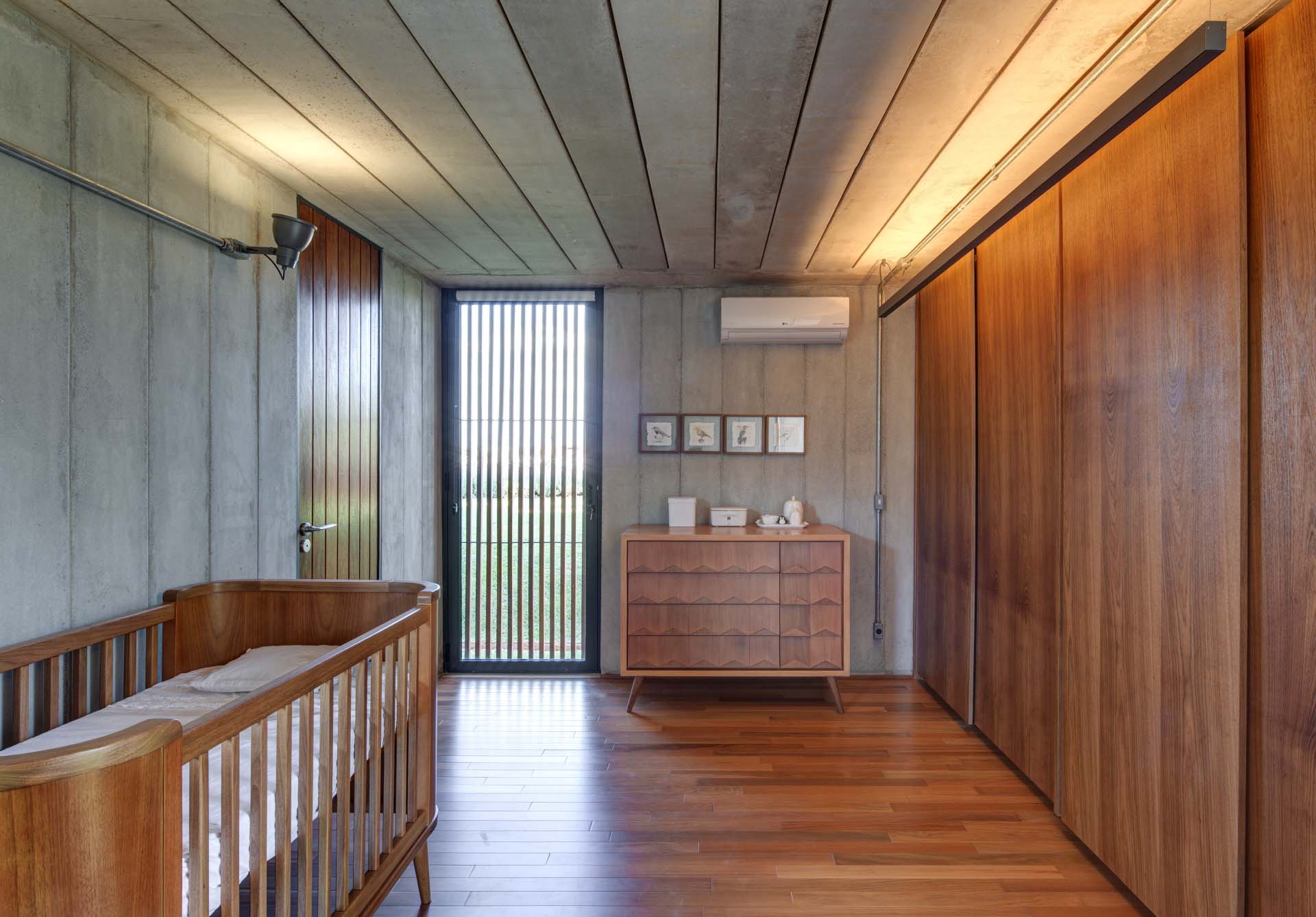 A modern nursery combines concrete walls with wood floors, cabinetry and accents.