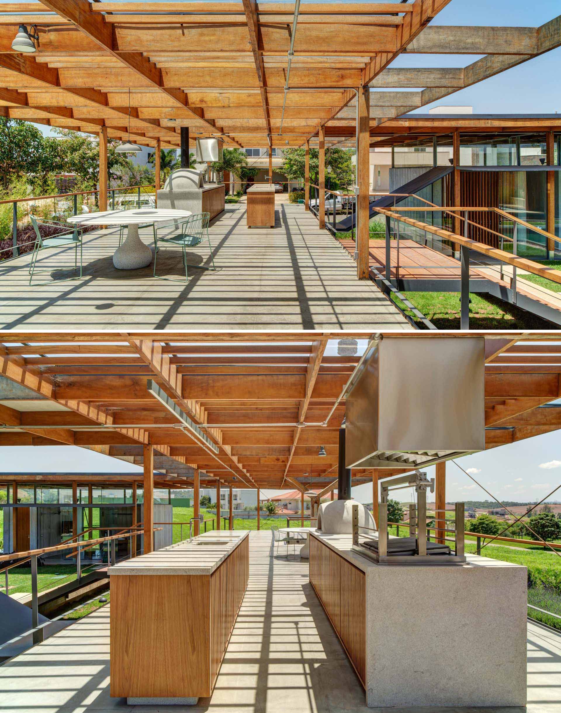 Stairs lead from the lawn and swimming pool up to a rooftop deck that has an outdoor kitchen and dining area. 