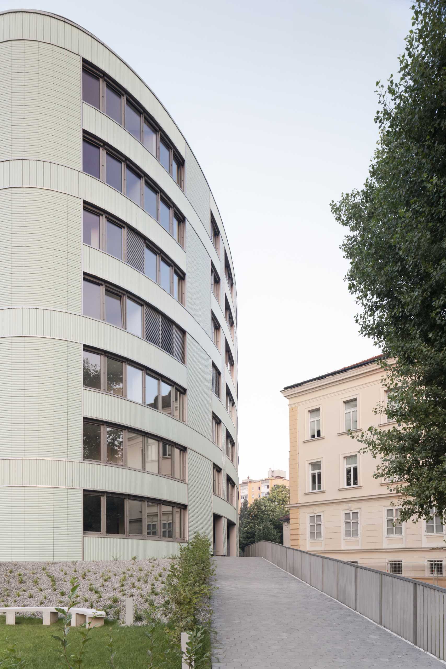 A modern residential building with undulating balconies and a facade covered in mint green tiles.