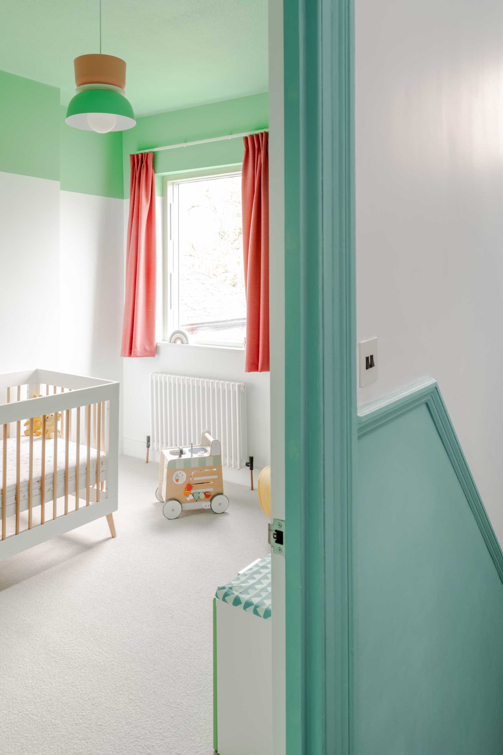 In this bedroom, there are green and white walls with a pop of contrasting color in the form of curtains.