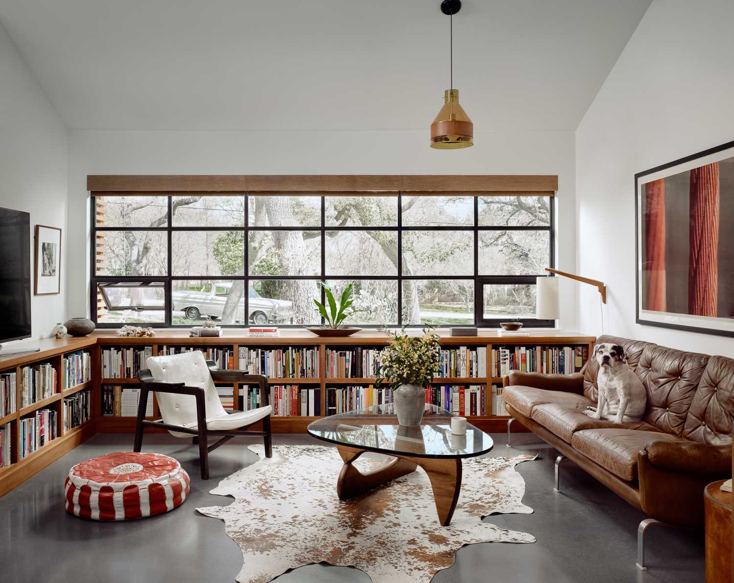 In the den, which was once a small bedroom, wood shelving wraps around the wall and below the windows, providing a place for the homeowner's book collection.