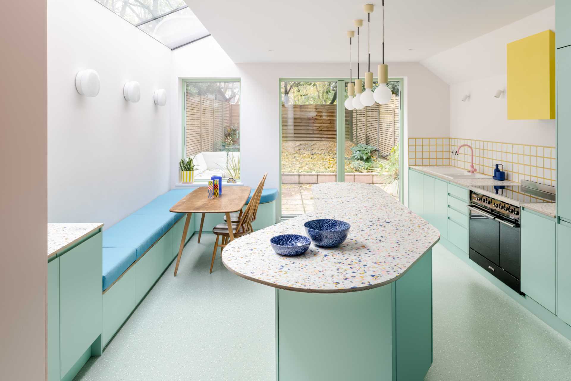 Inside the new addition, bespoke patterned worktops were ordered for the kitchen, which complement the pastel green cabinets, while the soft banquette seating was sewn by a local upholsterer.