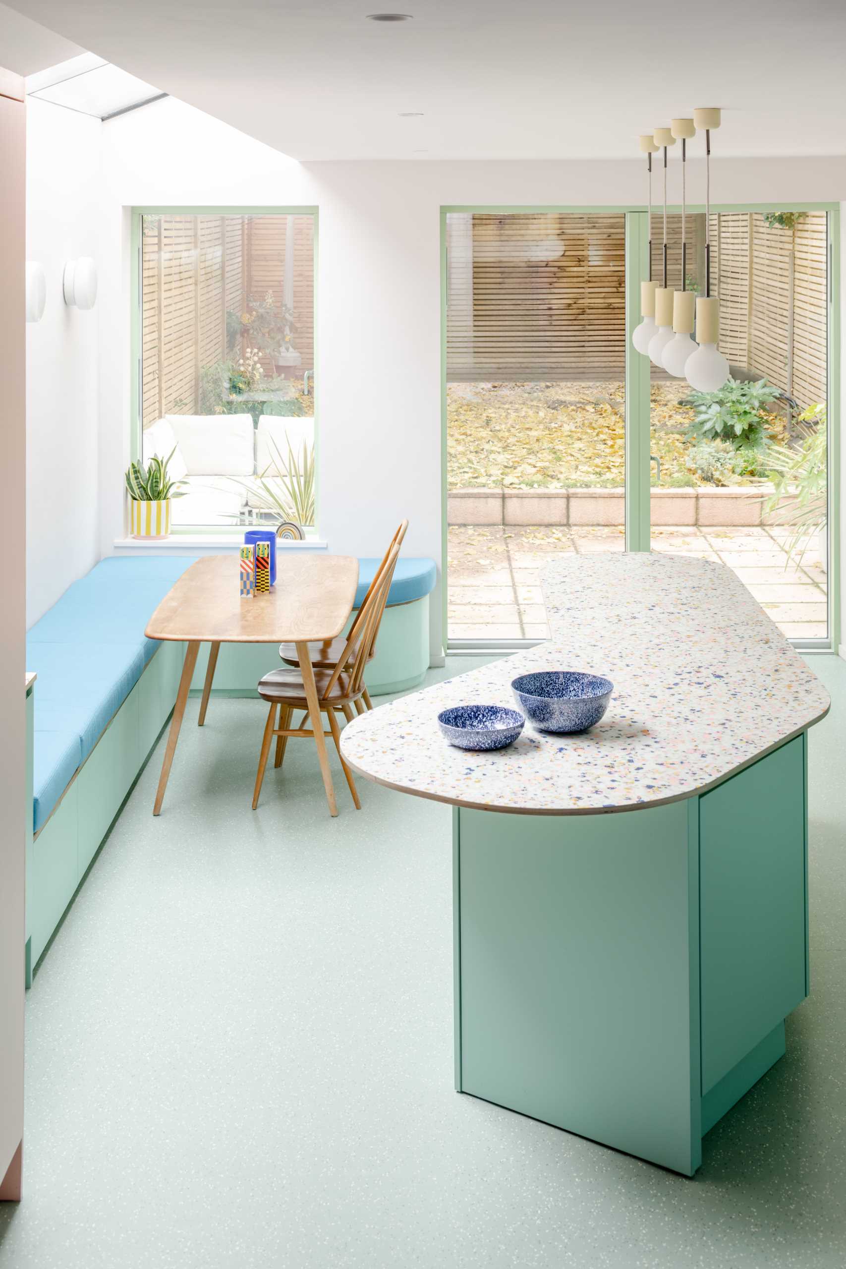 Inside the new addition, bespoke patterned worktops were ordered for the kitchen, which complement the pastel green cabinets, while the soft banquette seating was sewn by a local upholsterer.