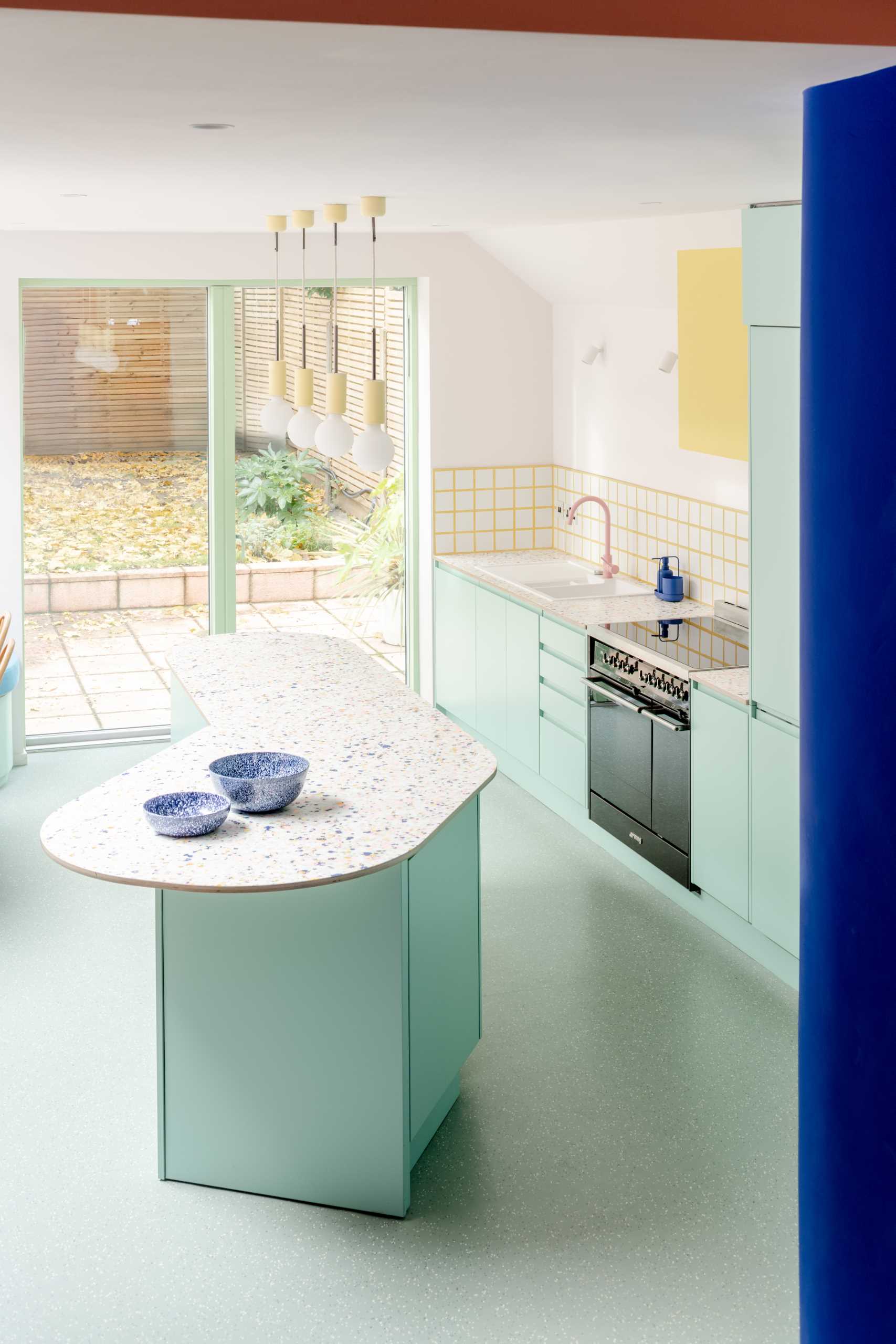 Inside the new addition, bespoke patterned worktops were ordered for the kitchen, which complement the pastel green cabinets, while the soft banquette seating was sewn by a local upholsterer.