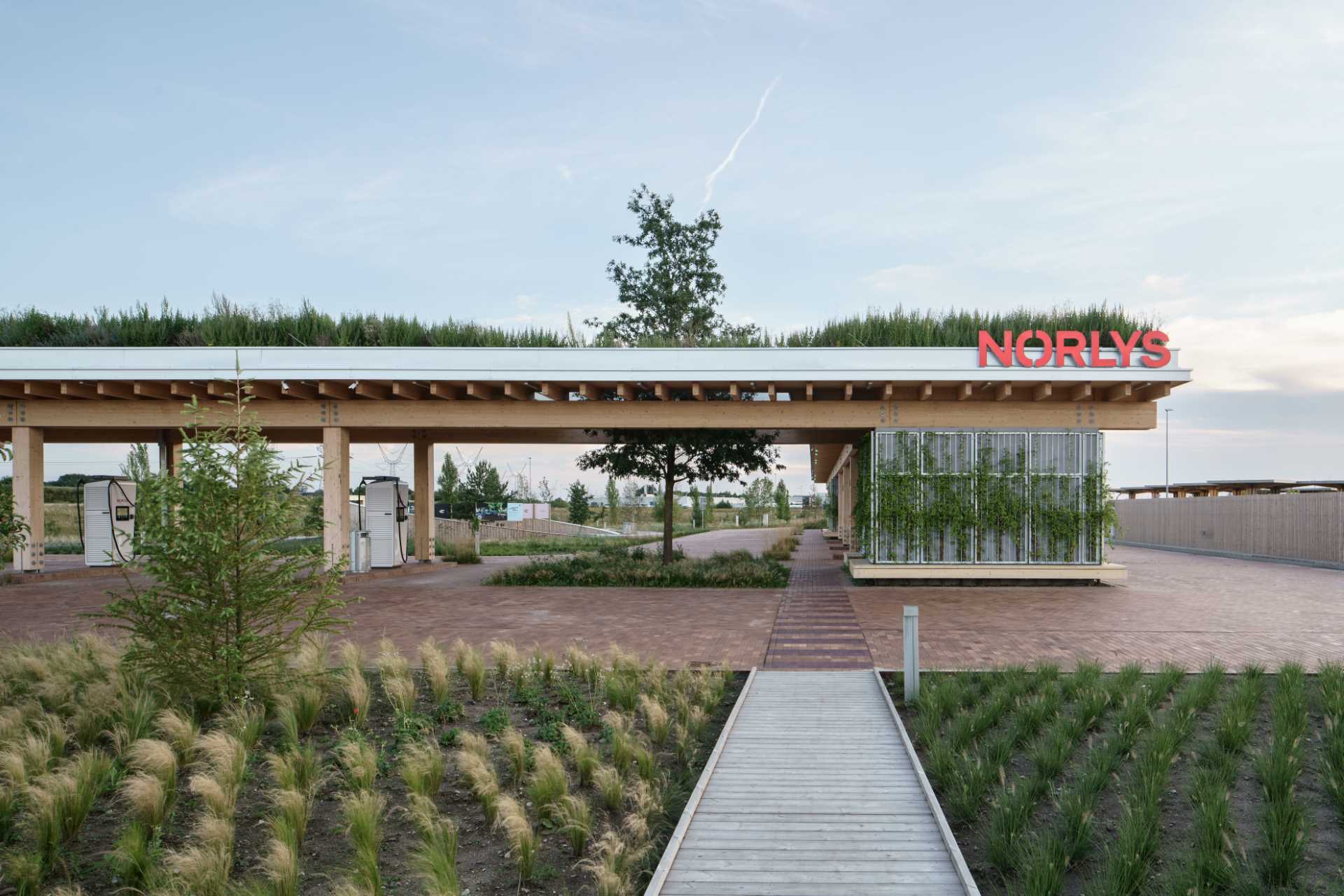 A contemporary charging station that includes a wood structure and a green roof.