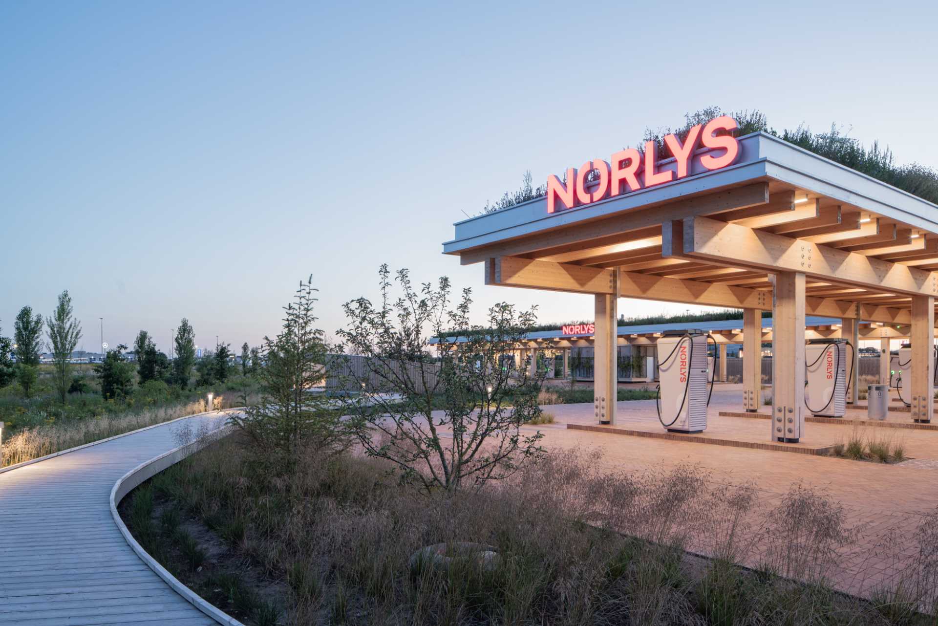 A contemporary charging station that includes a wood structure and a green roof.