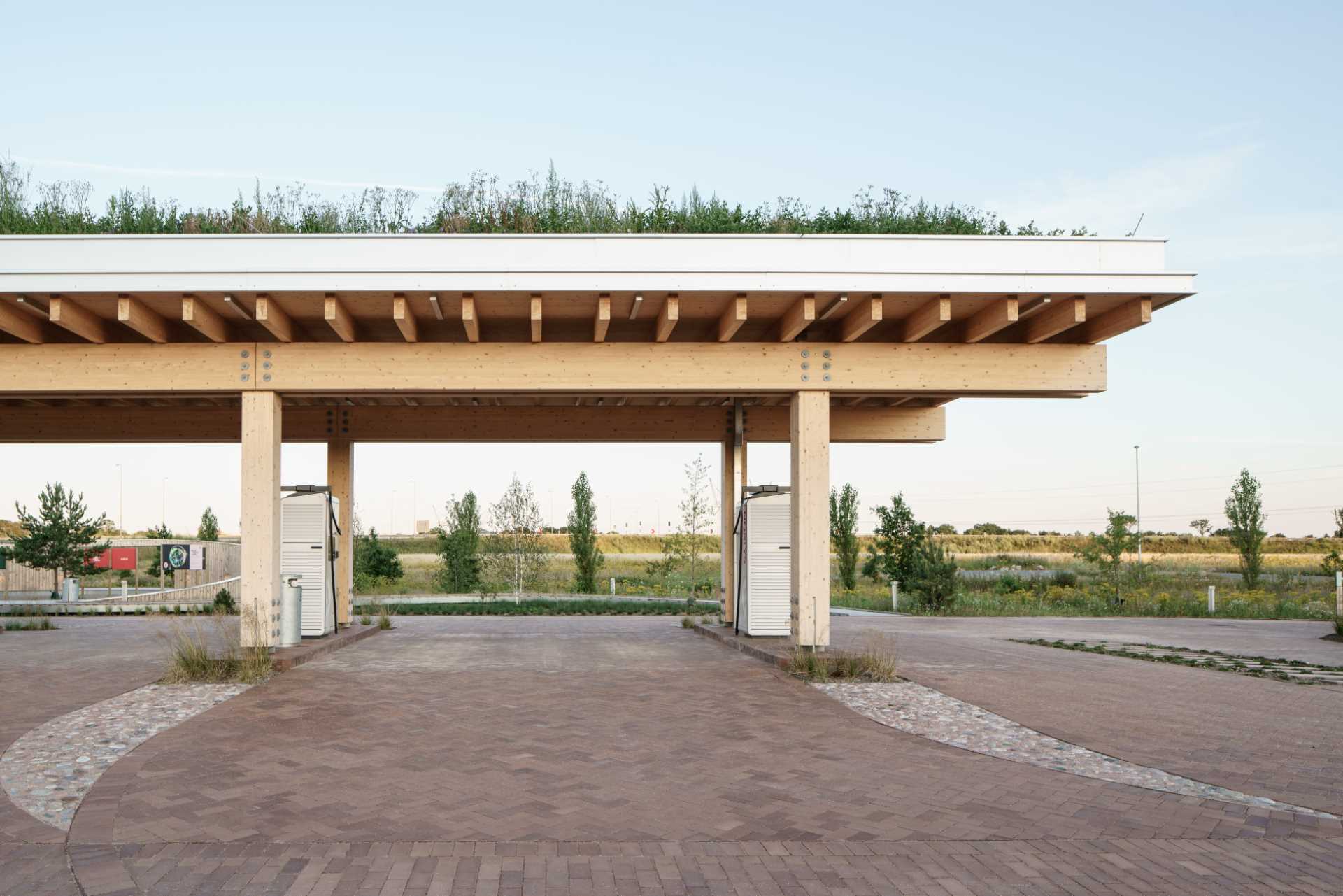 A contemporary charging station that includes a wood structure and a green roof.