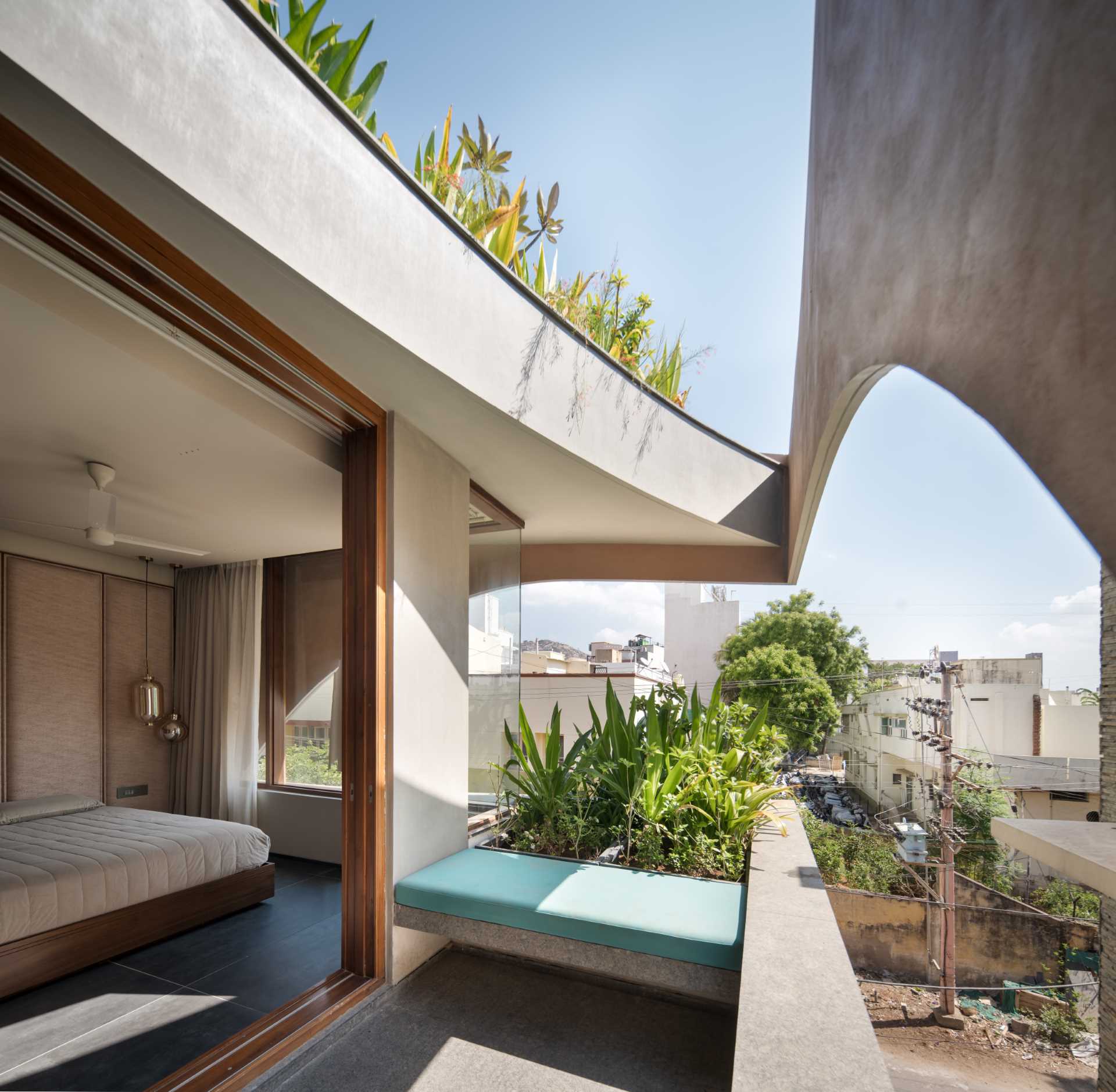 Upstairs in this modern home, there's a bedroom and a living room that both enjoy the views due to the cut-outs, while the balconies have built-in seating and planters that add greenery to the concrete surrounds.