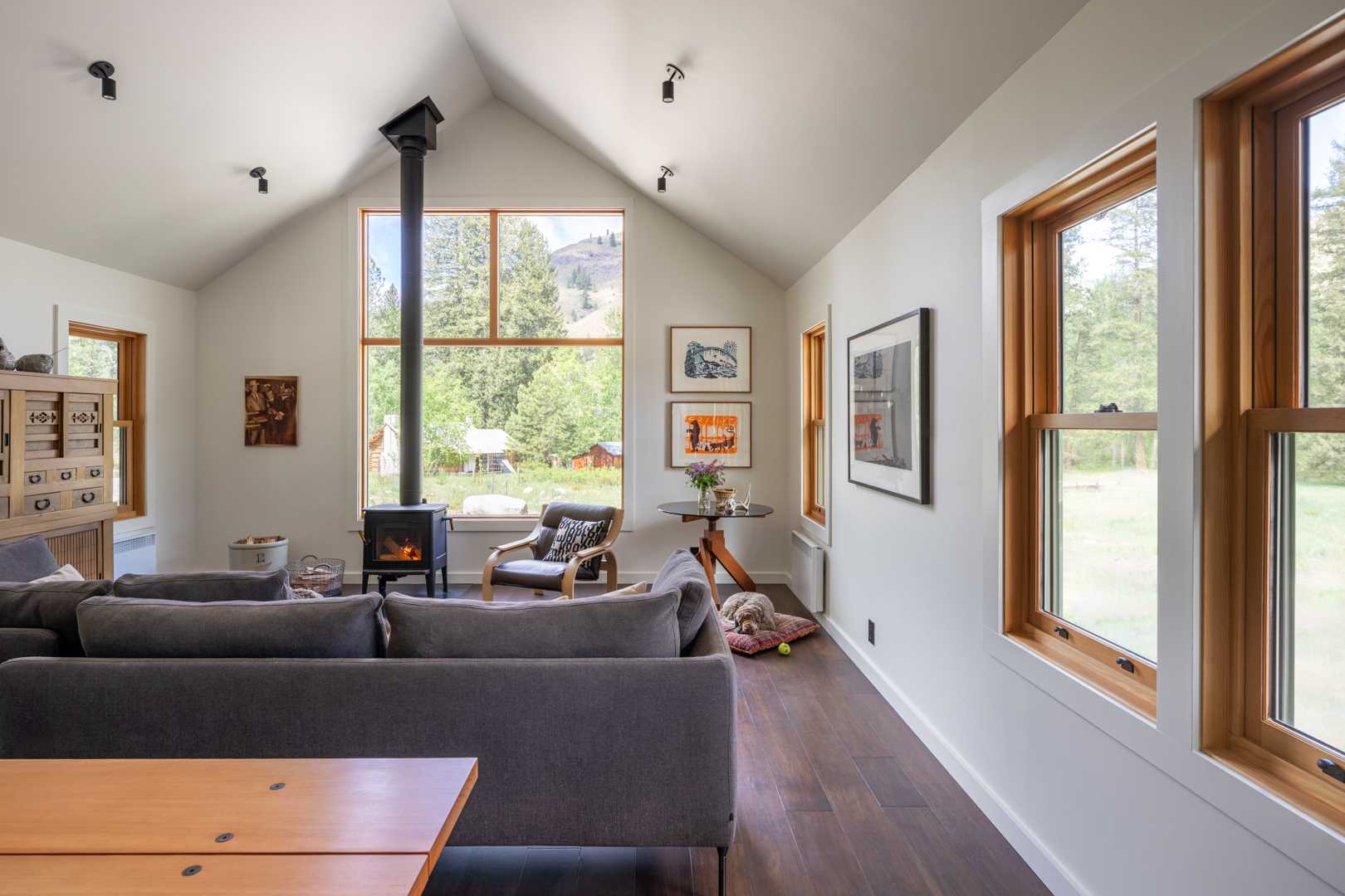 In this small home, there's an open-plan living room and dining area, with wood-framed windows highlighting the landscape.