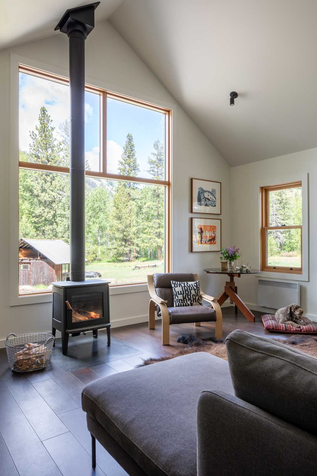 In this small home, there's an open-plan living room and dining area, with wood-framed windows highlighting the landscape.