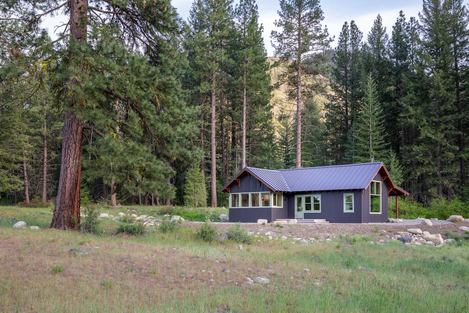 Metal roofing, siding, and a gravel skirt were chosen for this small house to reduce wildfire risk, and native plantings attract and support local birds and wildlife.