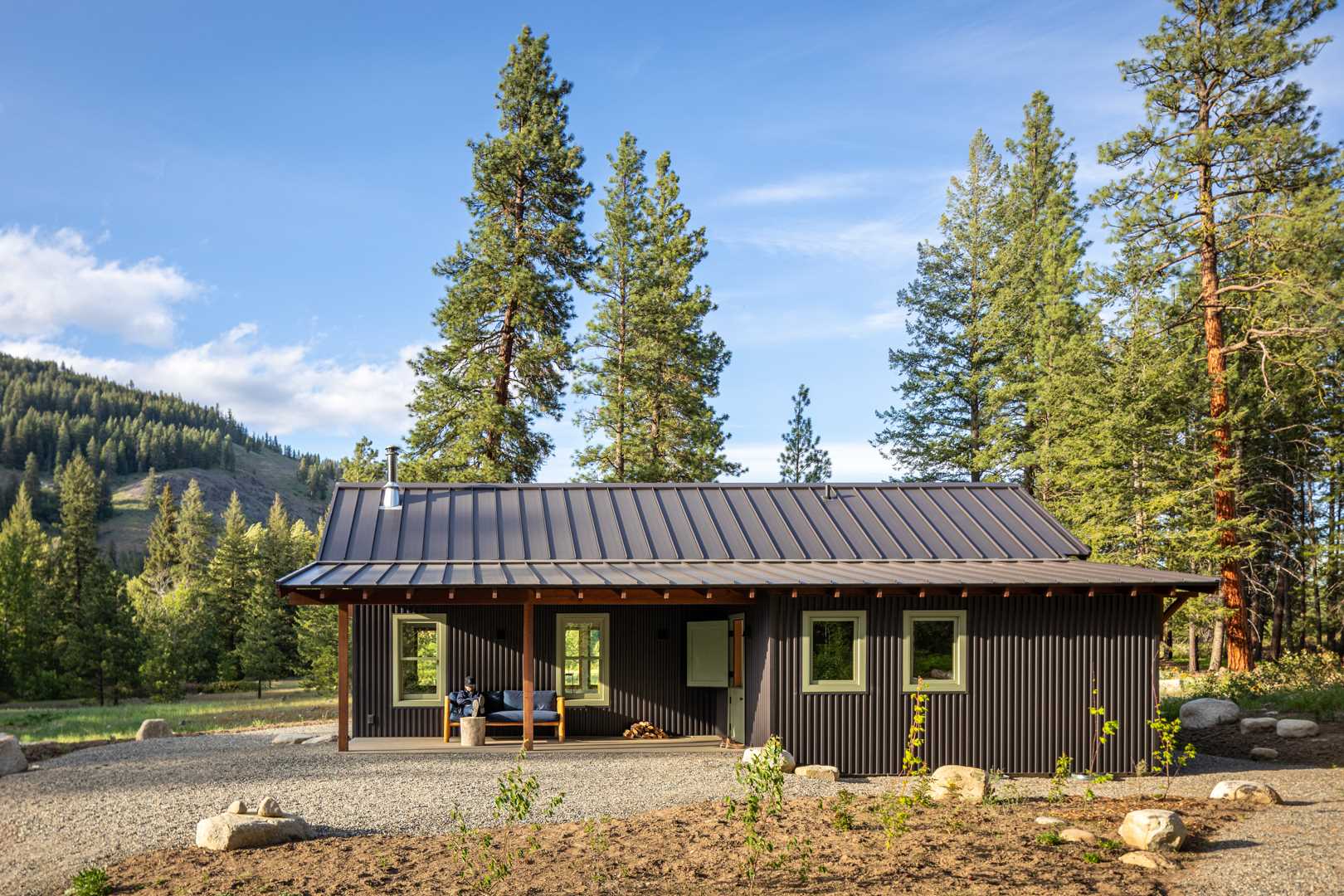 Metal roofing, siding, and a gravel skirt were chosen for this small house to reduce wildfire risk, and native plantings attract and support local birds and wildlife.