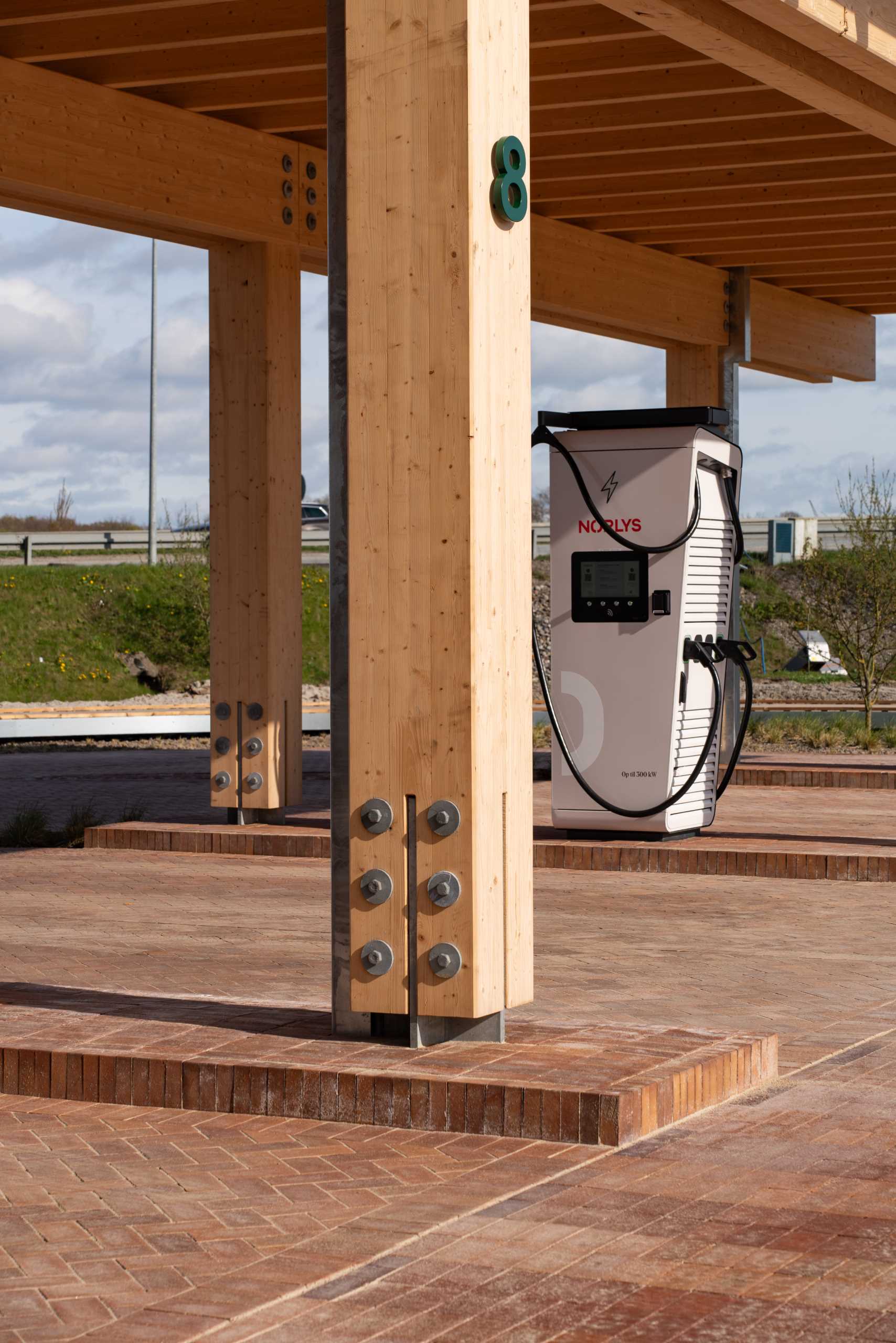 A contemporary charging station that includes a wood structure and a green roof.