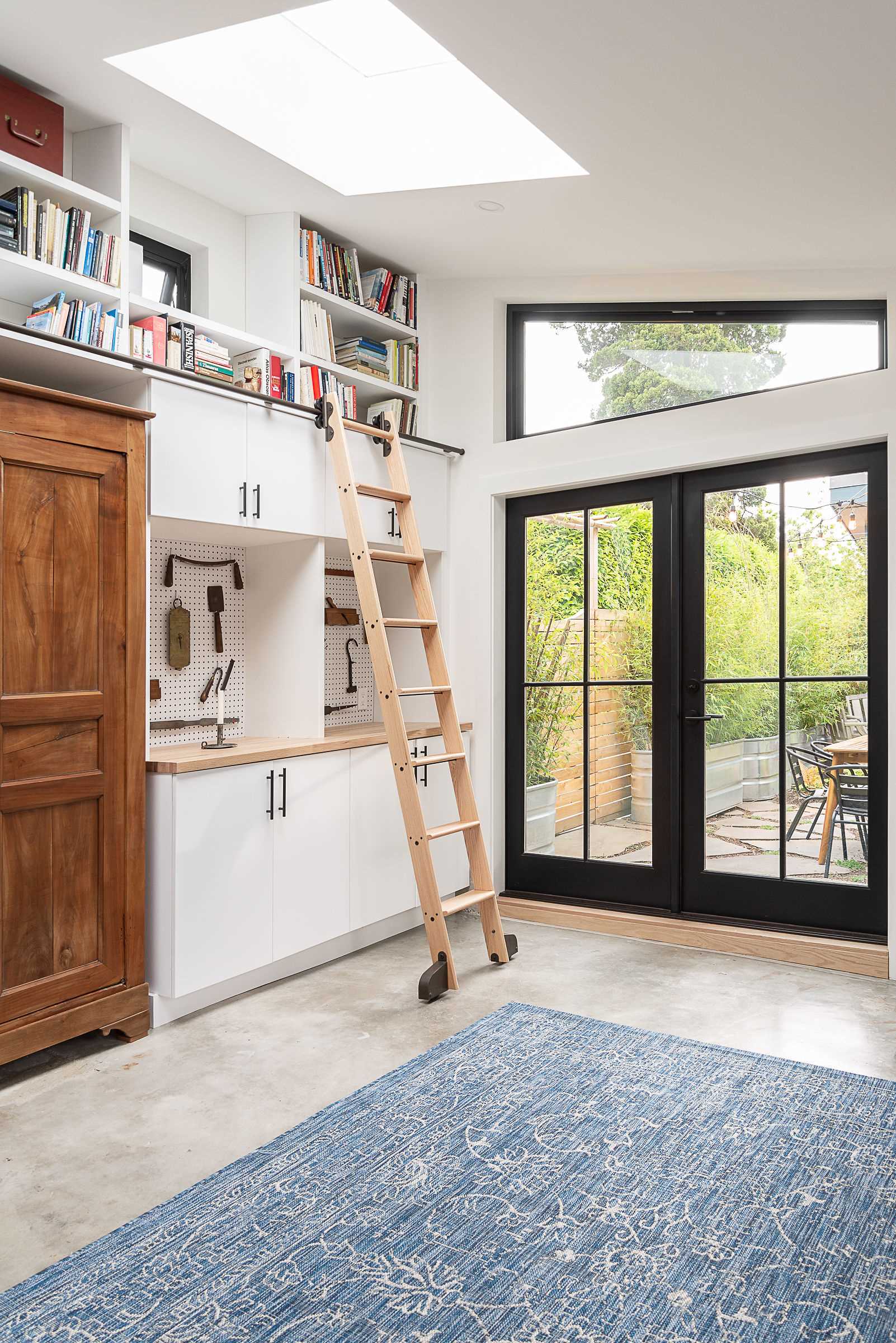 A backyard cottage designed as a home office includes a rolling ladder.