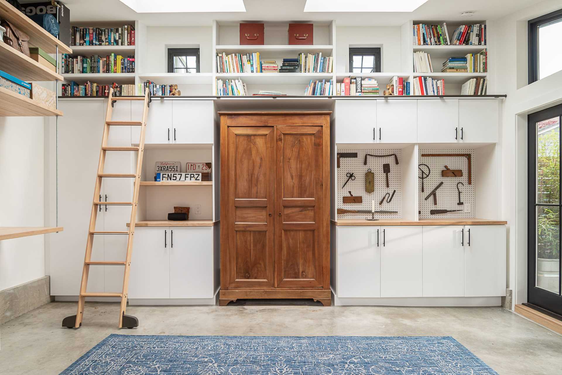 A backyard cottage designed as a home office includes a rolling ladder.