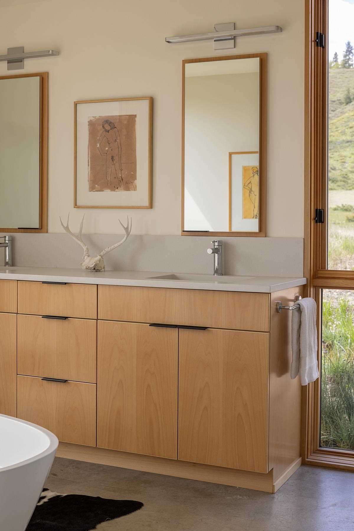 In this contemporary primary en-suite bathroom, there's a double vanity with tall mirrors, as well as a freestanding bathtub and concrete flooring.