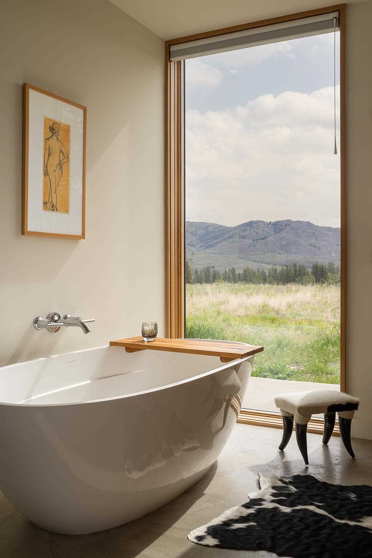 In this contemporary primary en-suite bathroom, there's a double vanity with tall mirrors, as well as a freestanding bathtub and concrete flooring.