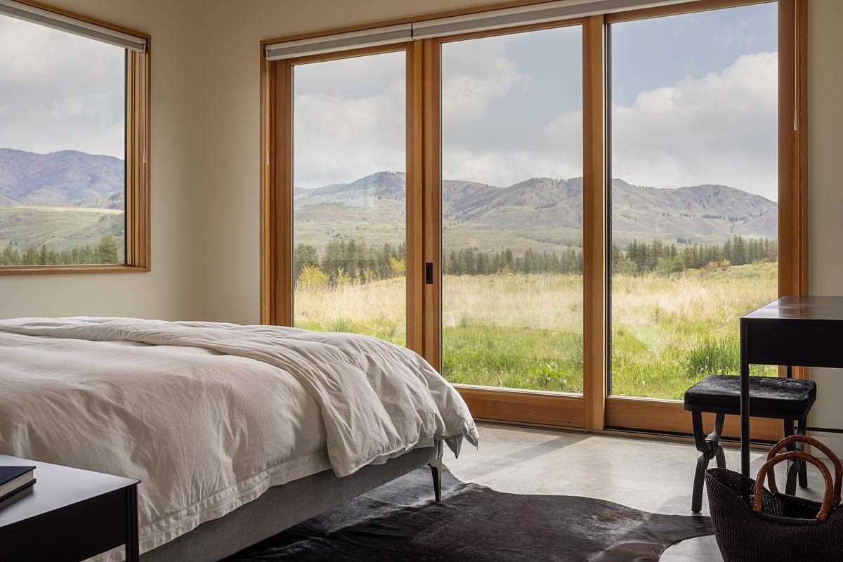 In this bedroom, the glass doors and windows frame the views of the surrounding landscape.