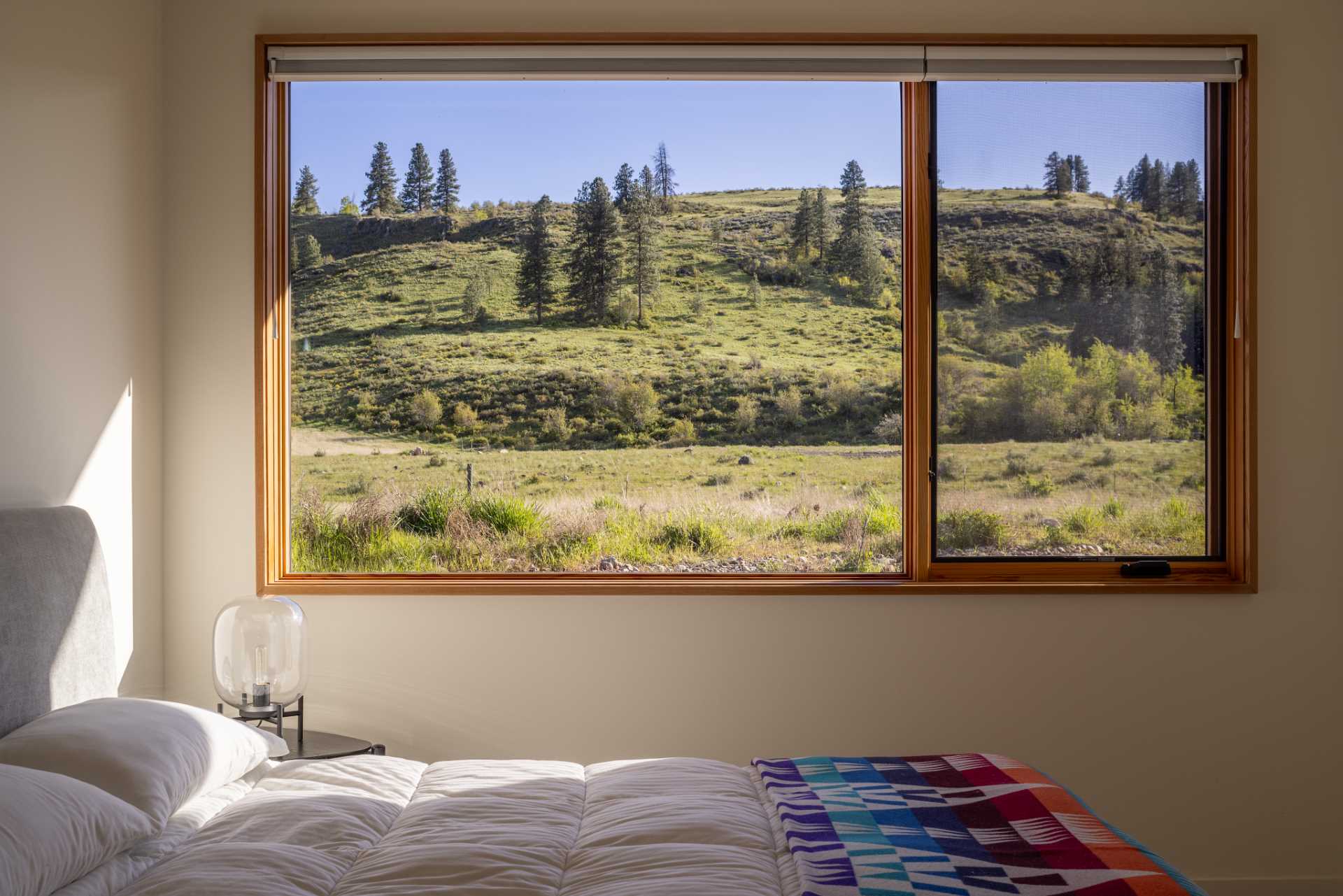 In this bedroom, the windows frame the views of the surrounding landscape.