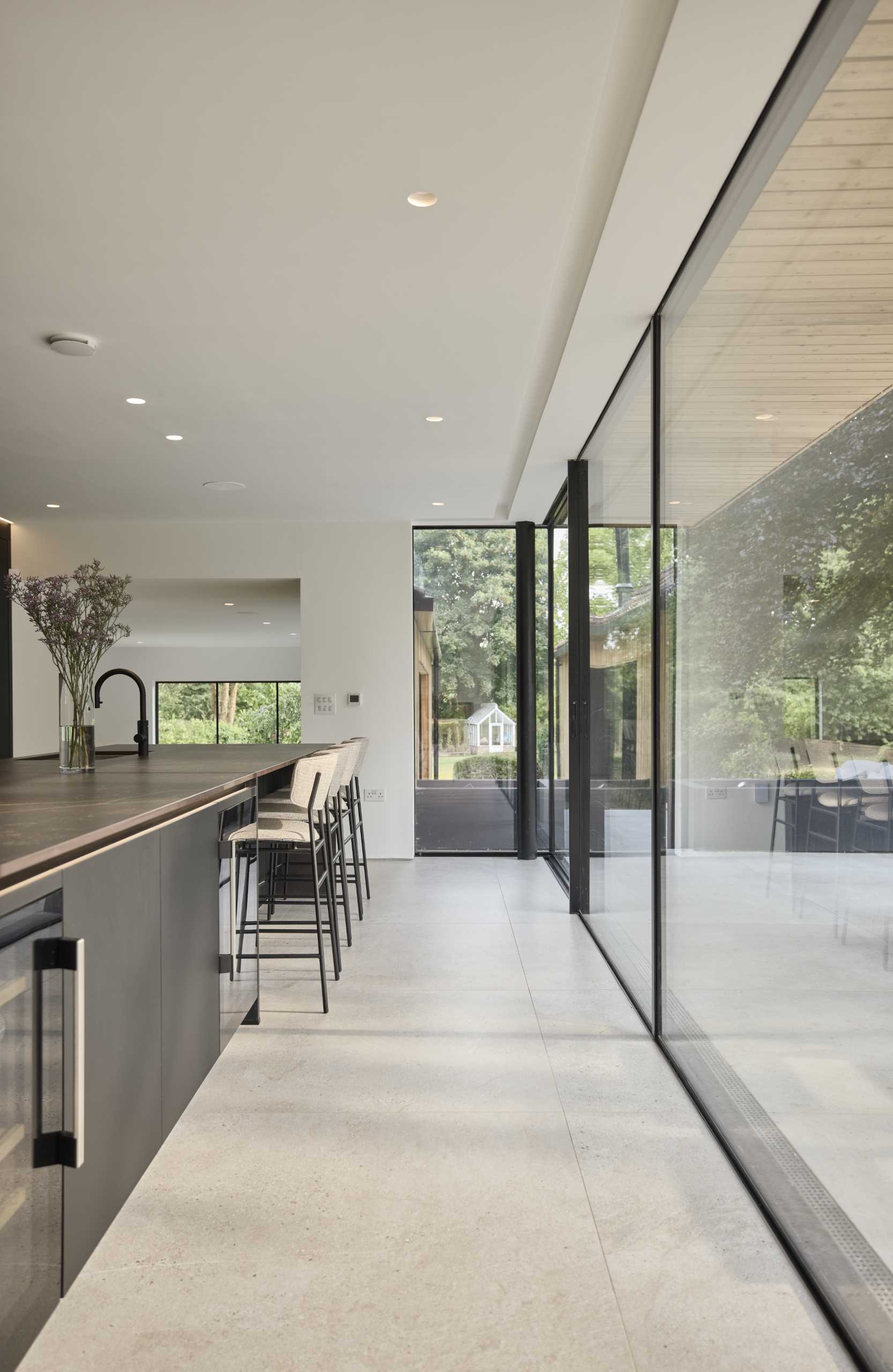 The cantilevered first floor shelters the expansive glass sliding doors below that connect the kitchen with the patio.