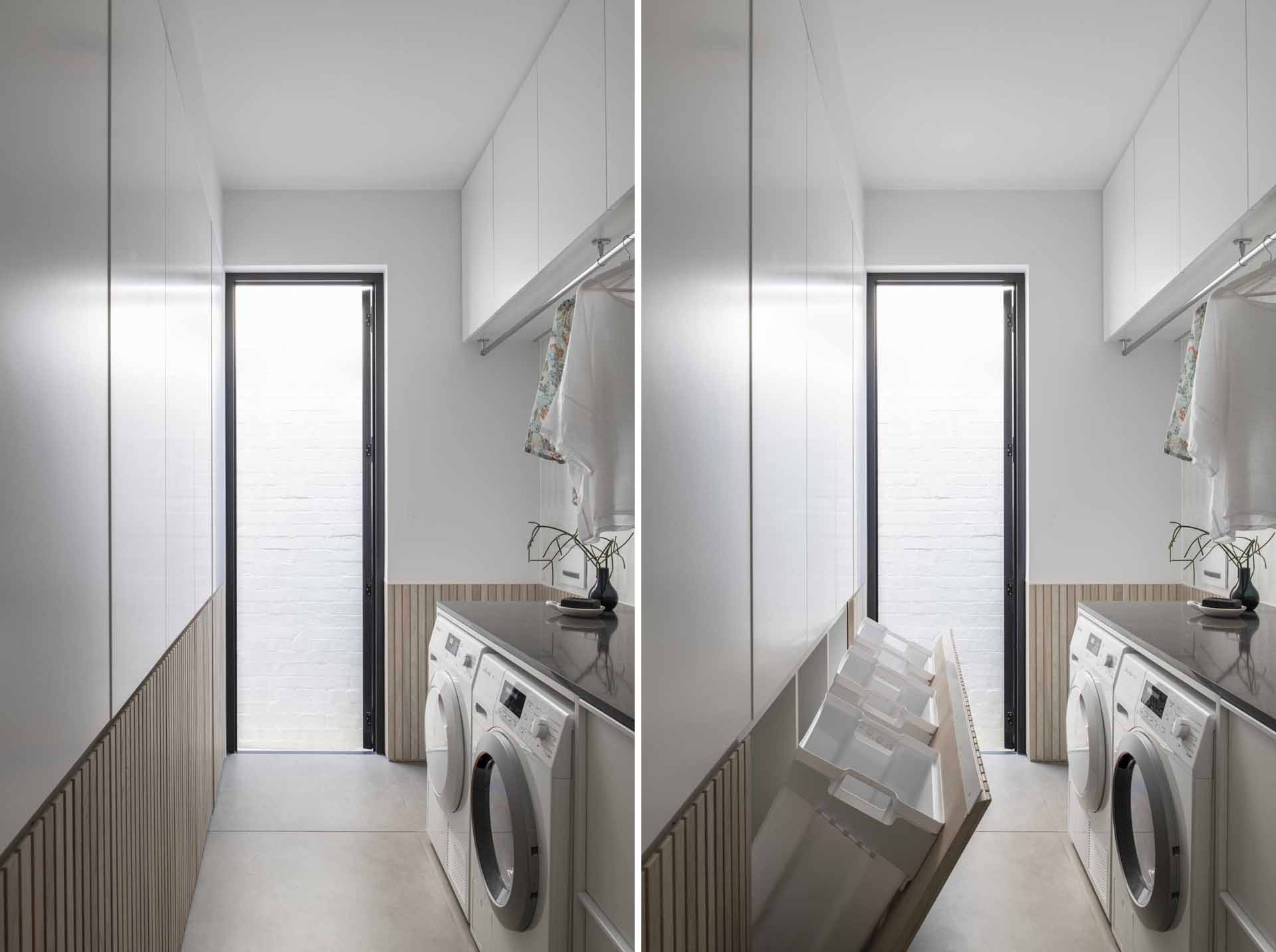 A modern white laundry room with wood paneling that hides three laundry baskets below cabinetry.