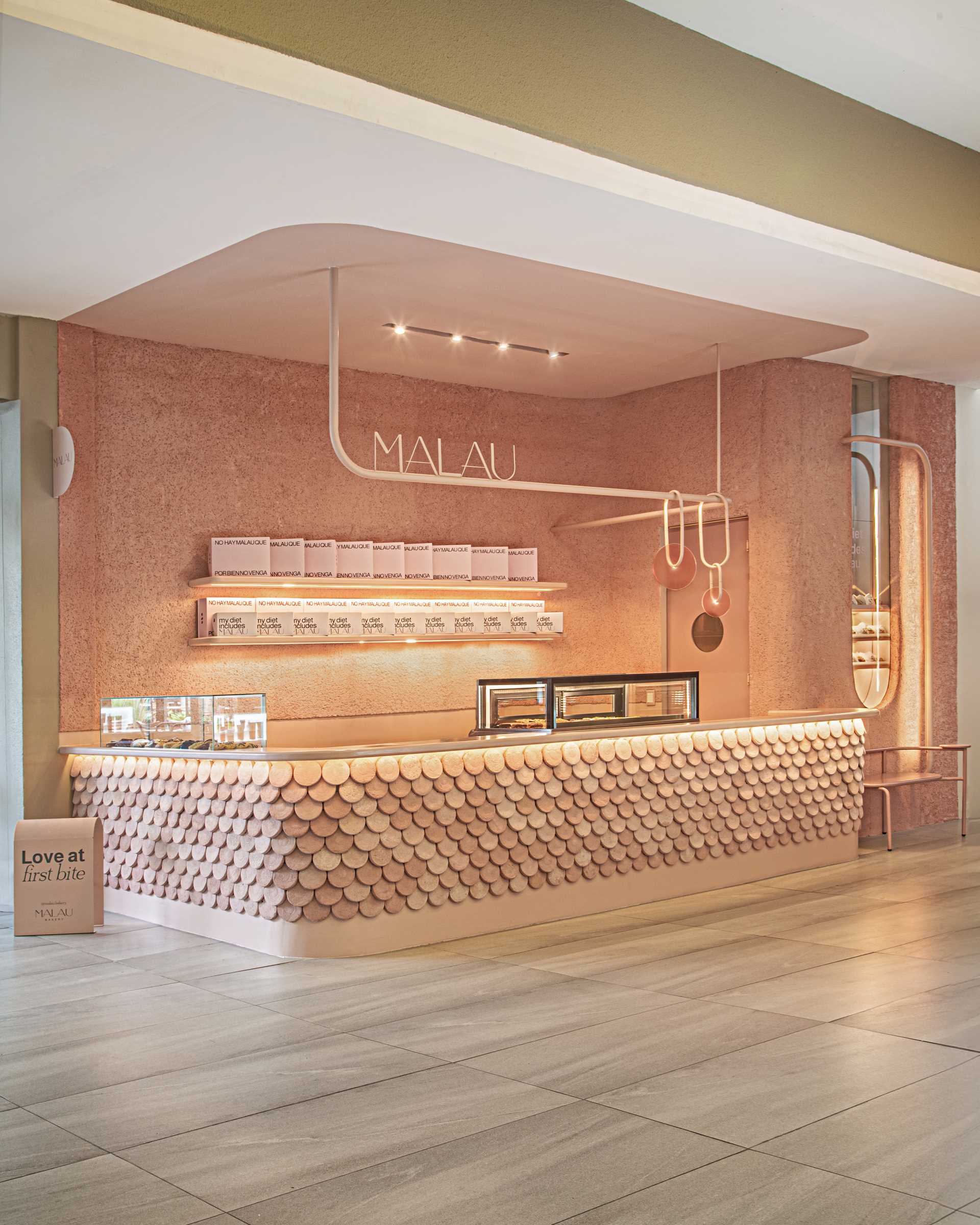 A modern bakery with a pastel pink colour palette, also includes handcrafted pieces of dyed cement that make up the cladding of the bar front.