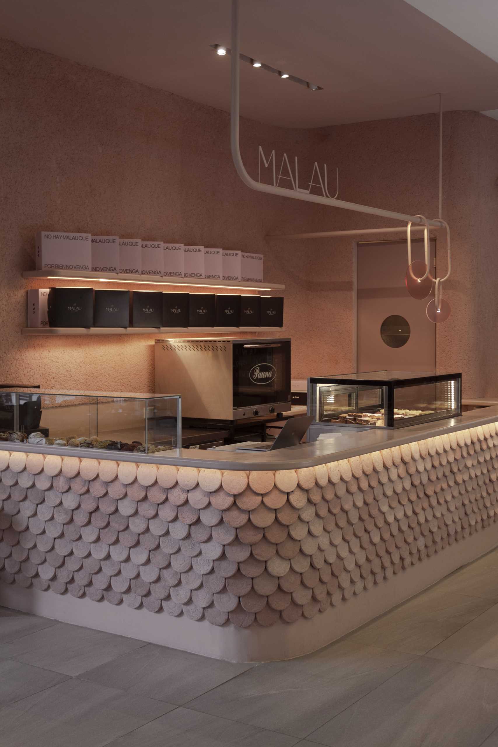 A modern bakery with a pastel pink colour palette, also includes handcrafted pieces of dyed cement that make up the cladding of the bar front.