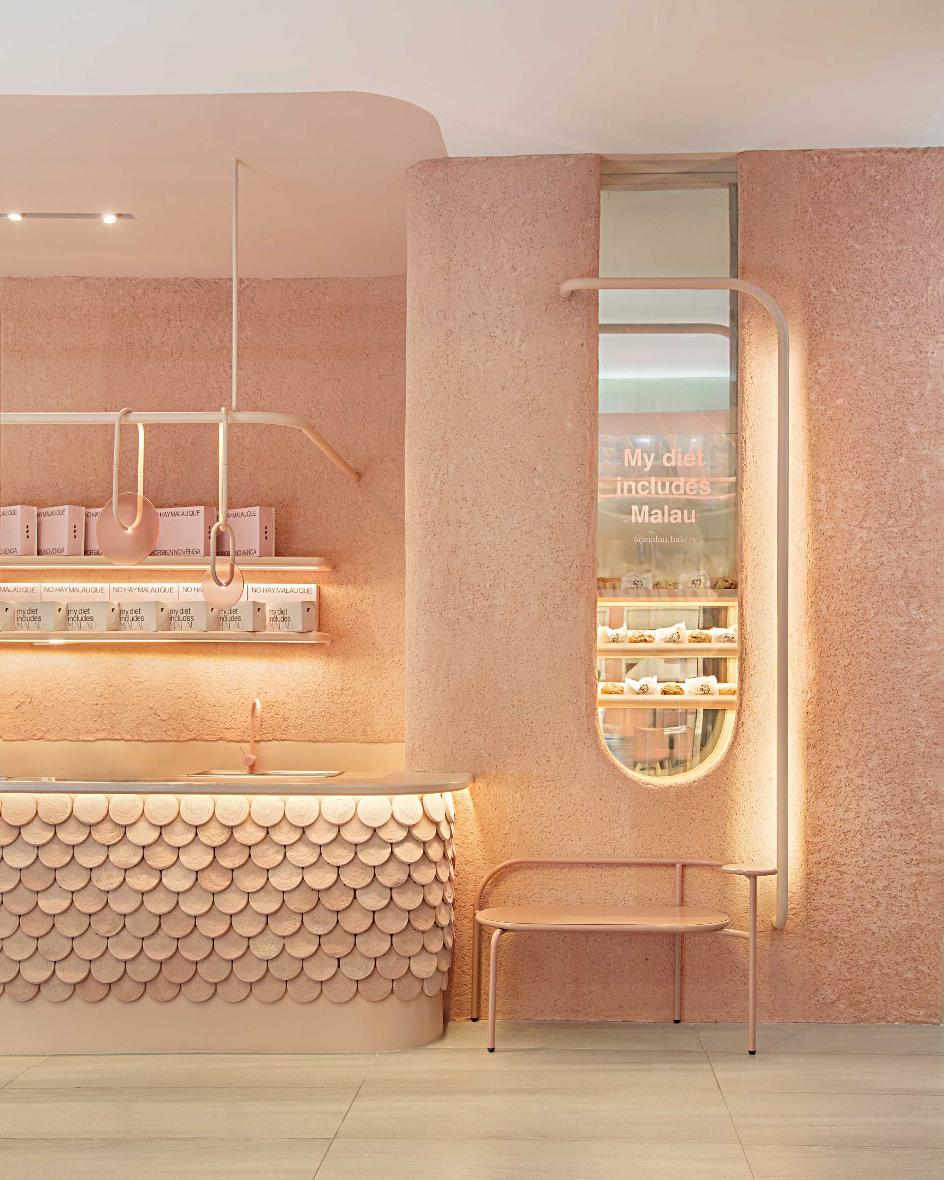 A modern bakery with a pastel pink colour palette, also includes handcrafted pieces of dyed cement that make up the cladding of the bar front.