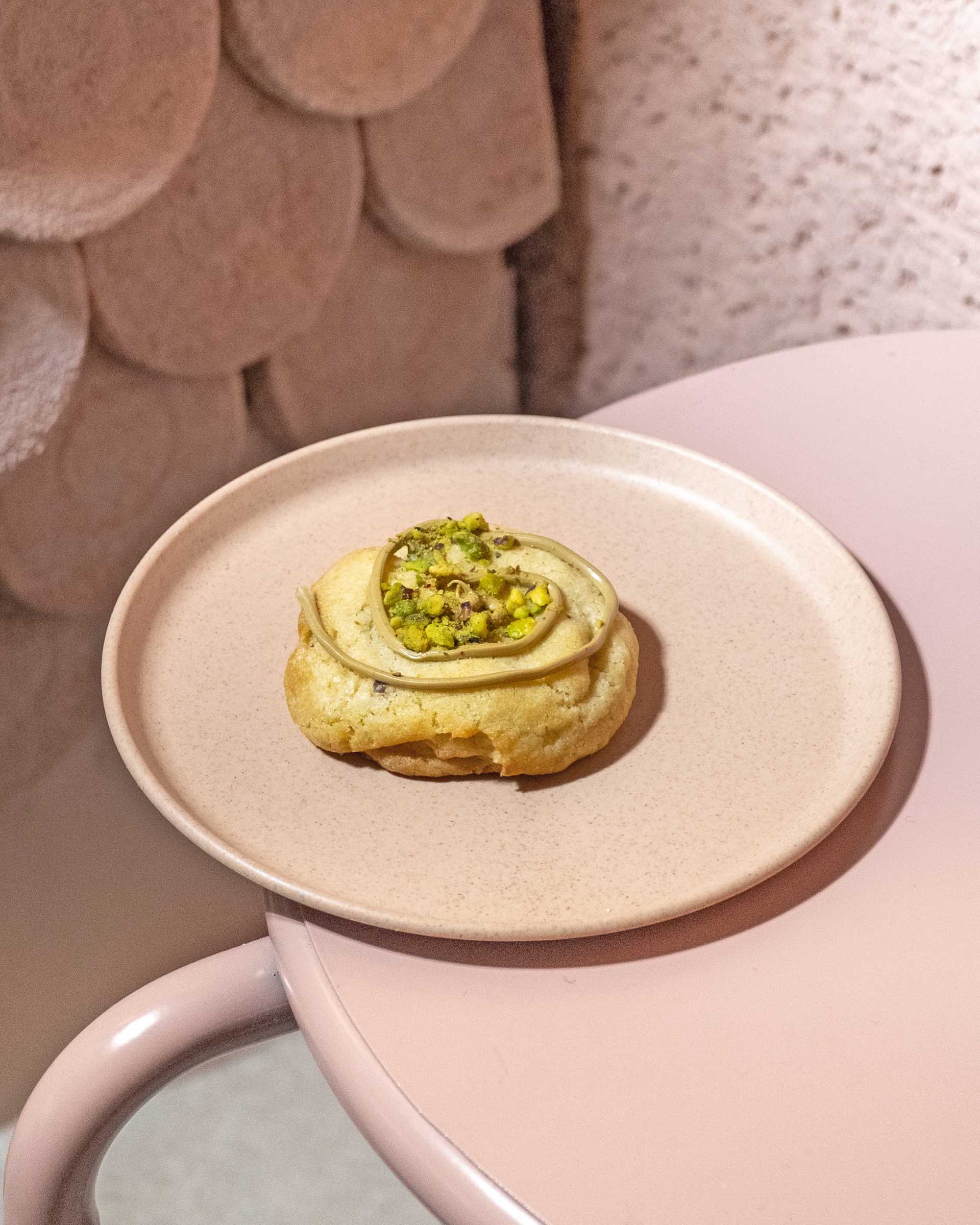 A modern bakery with a pastel pink colour palette, also includes handcrafted pieces of dyed cement that make up the cladding of the bar front.