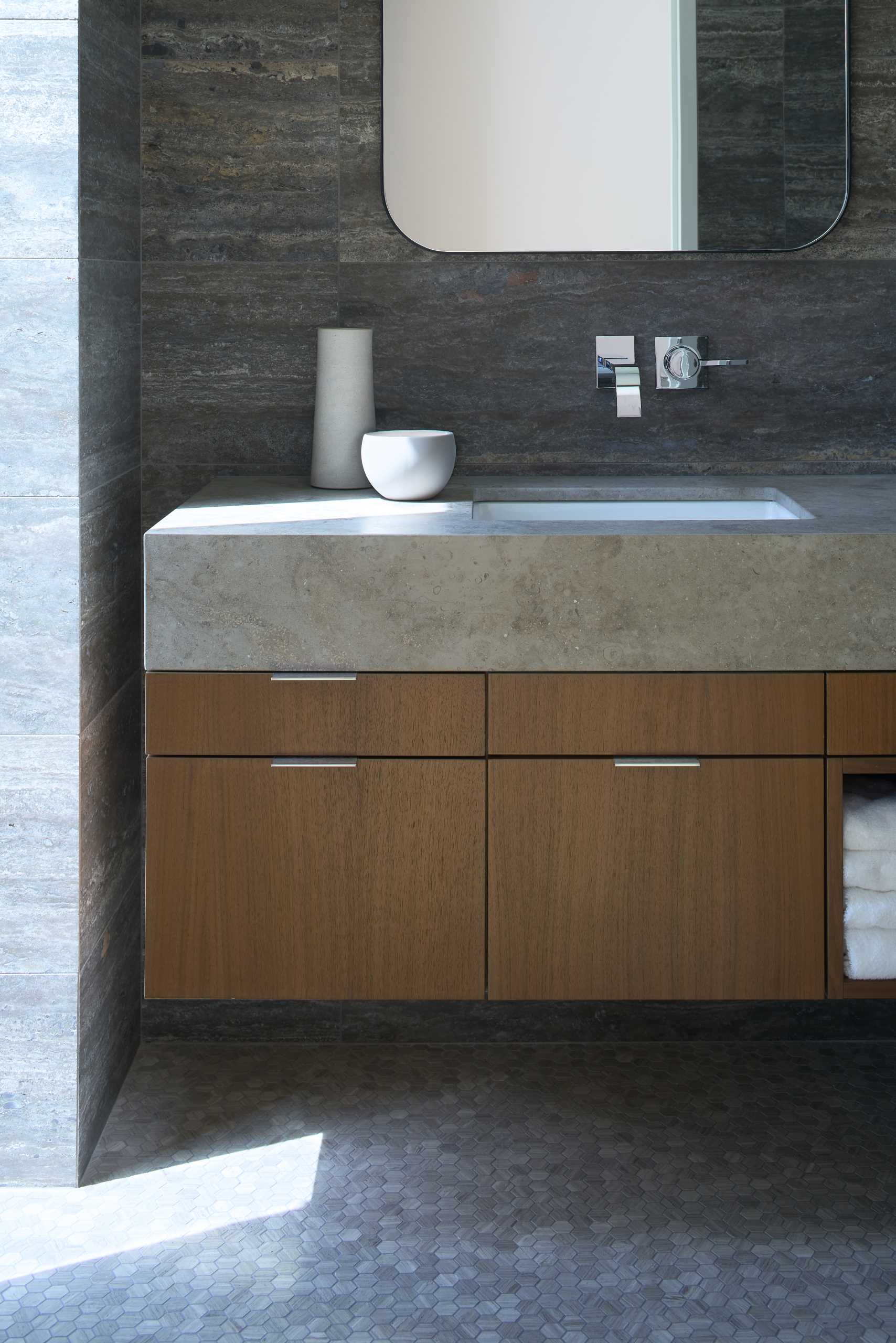 A modern bathroom with stone walls and vanity.