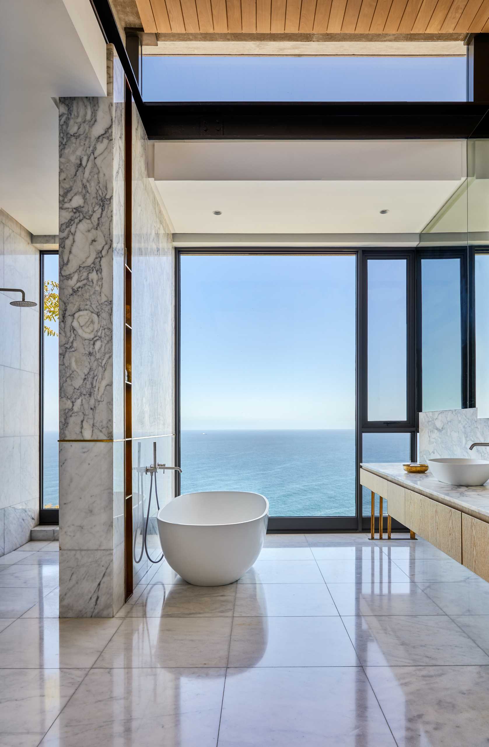 A modern bathroom with a freestanding bathtub positioned for the views.