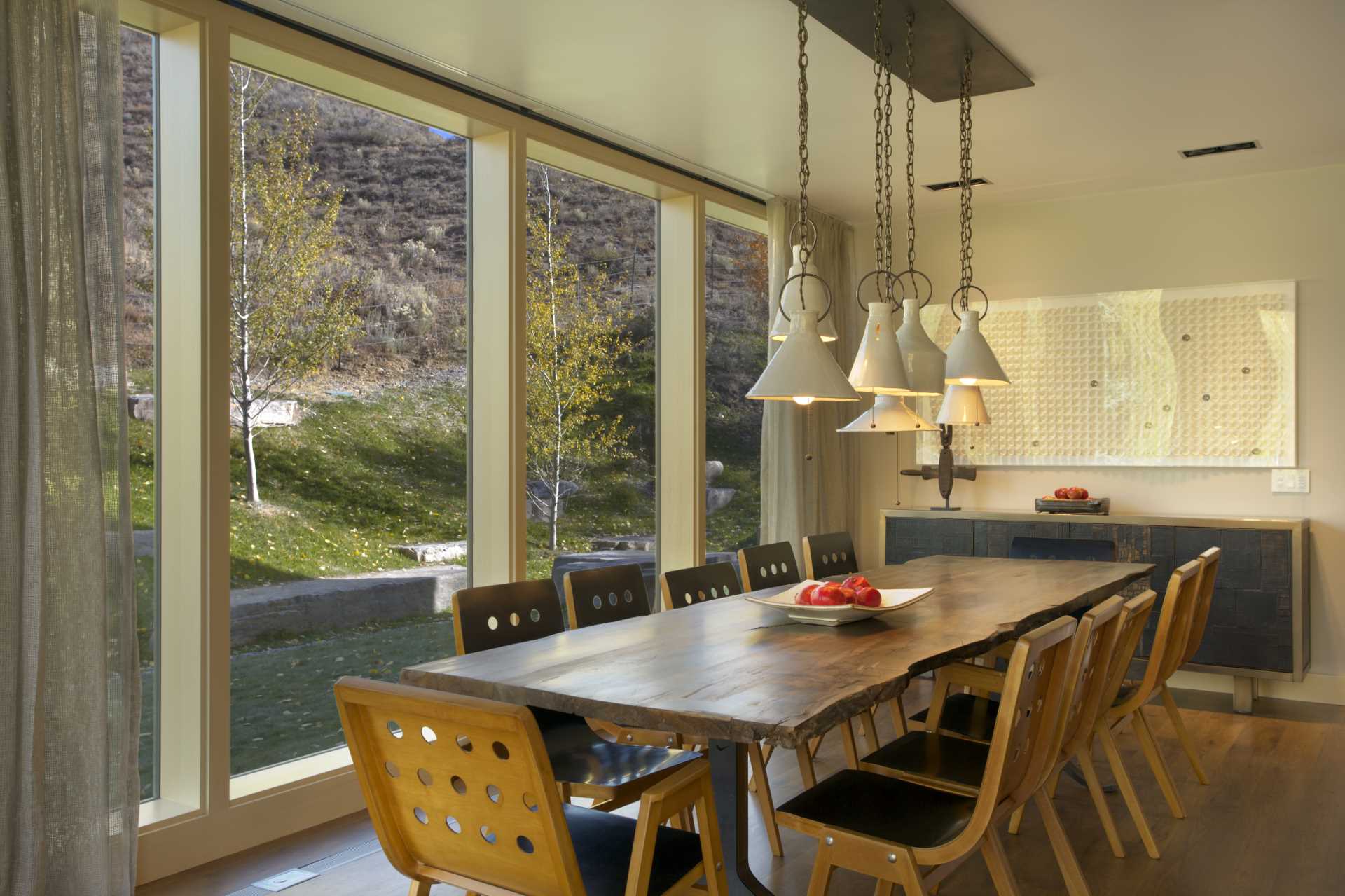 In this dining room, floor-to-ceiling windows frame the views, while a live edge dining table provides seating for ten.