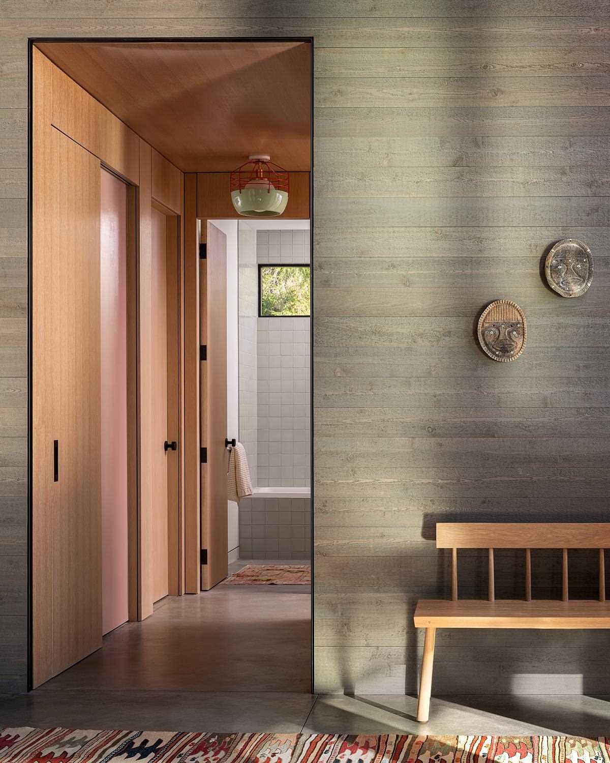 This entryway has a bench and wood walls, and leads to the bedrooms and bathrooms.