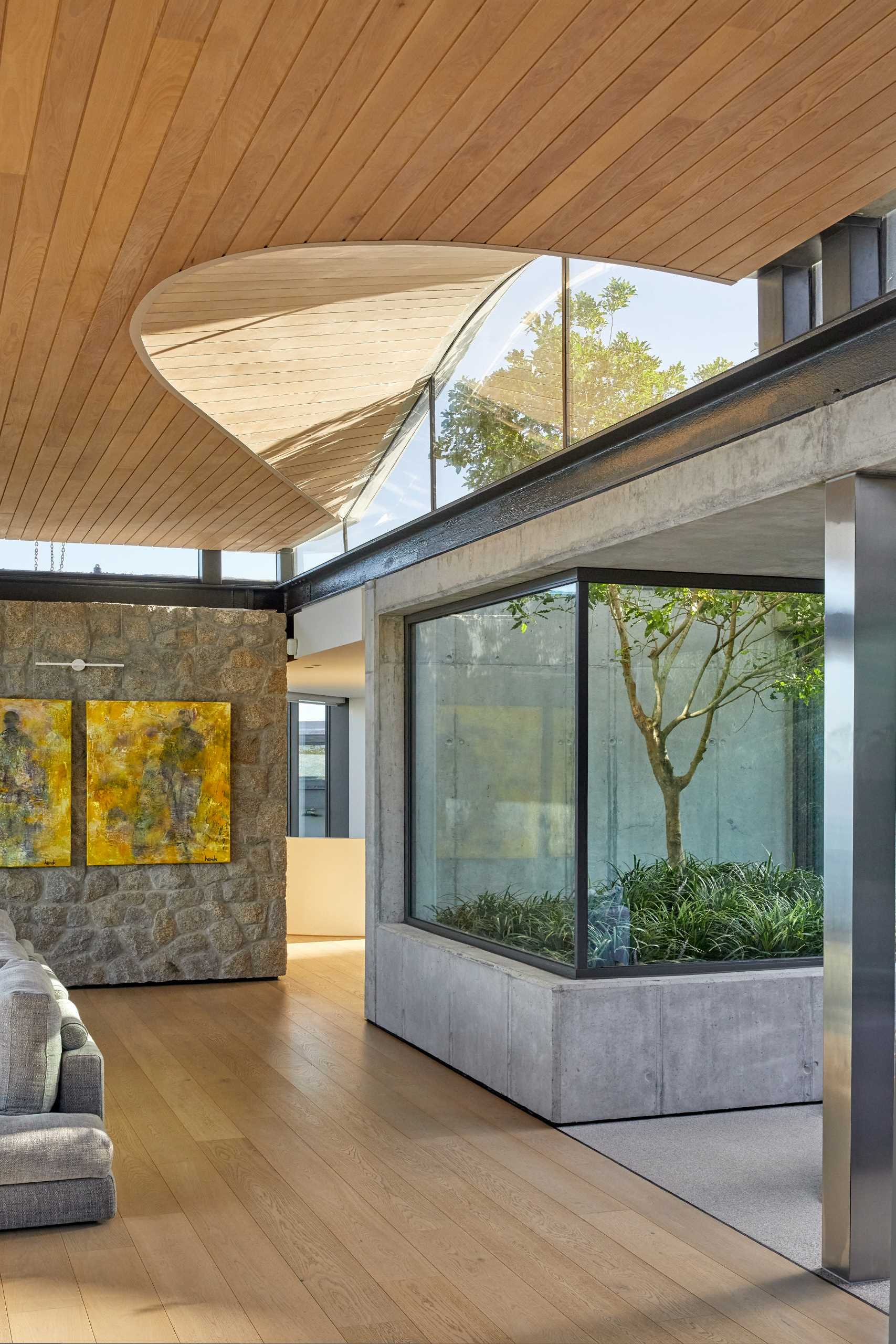 A modern home interior with clerestory windows and an undulating wood-lined ceiling.